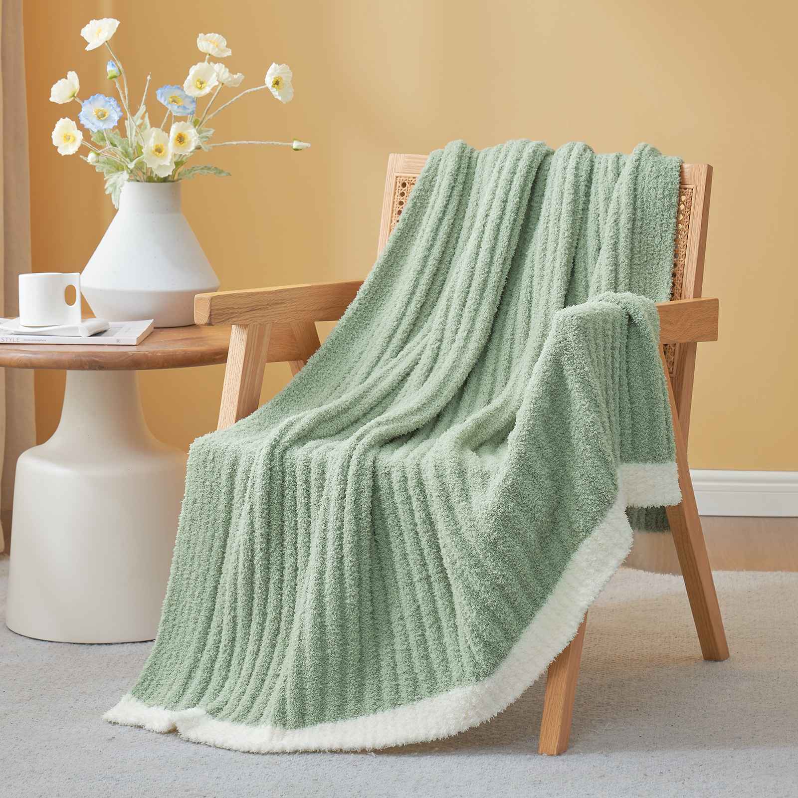 Snuggle Sac UltraSoft Ribbed Feather Yarn Knit Throw Blanket draped on the chair with a vase of flower#Color_Sage Green