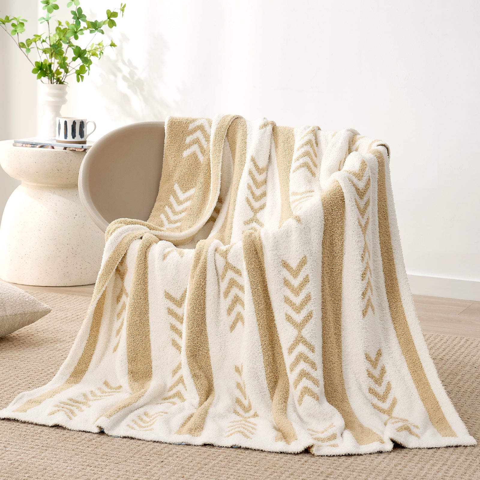 Snuggle Sacs Reversible Boho Feather Yarn Knit Throw Blanket draped on a grey chair with plant behind#color_beige