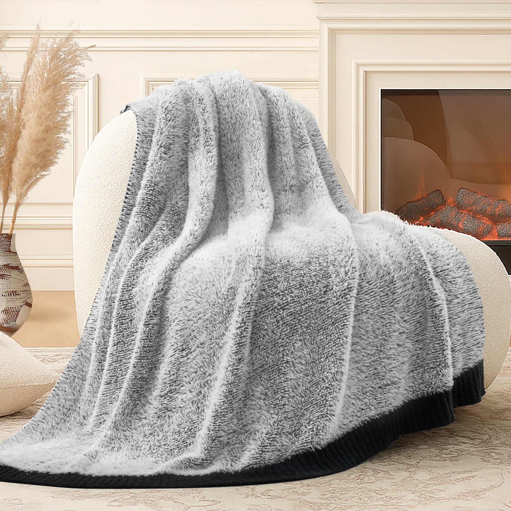 Snuggle Sac ultrasoft faux fur knit throw blanket in Black draped over a sofa near a fireplace, creating a warm and cozy atmosphere #color_Black