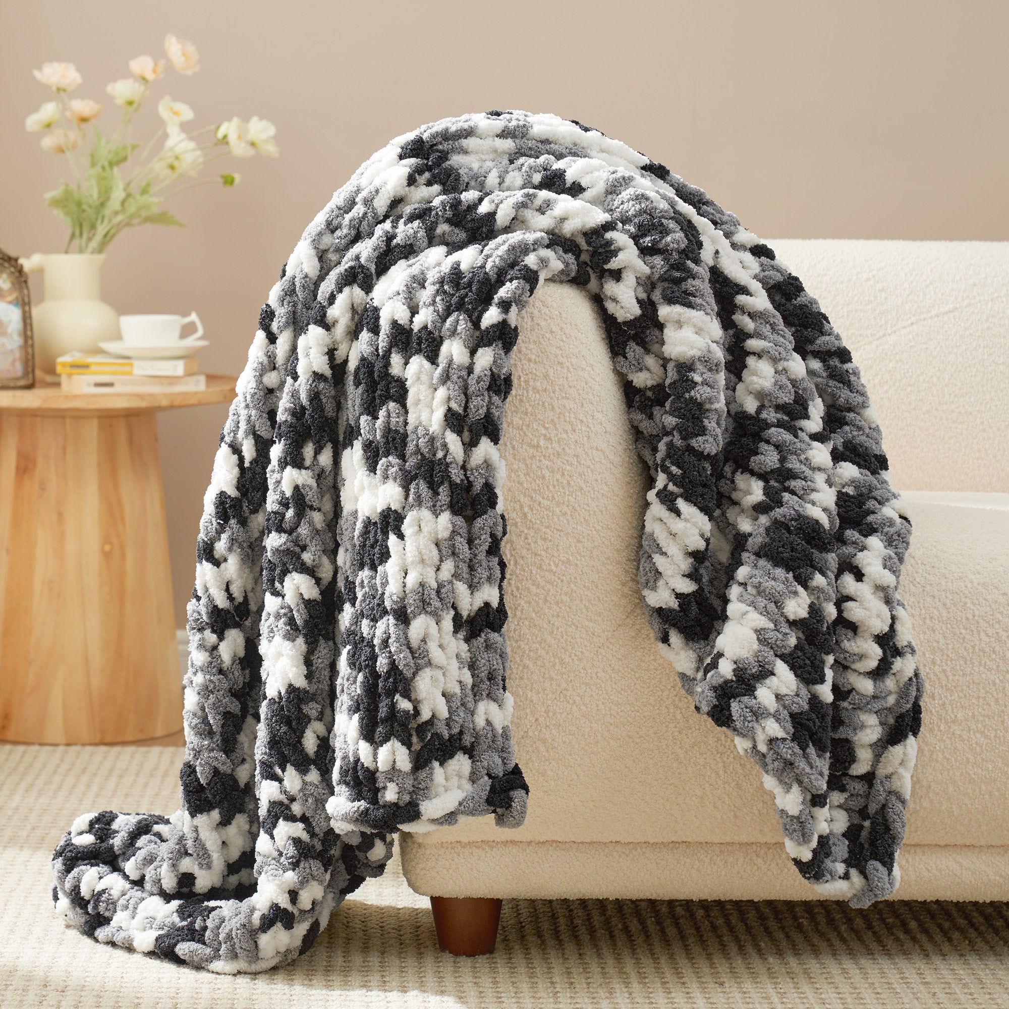Striped chunky chenille knit throw blanket in Black draped over a sofa, creating a warm atmosphere. #color_Black