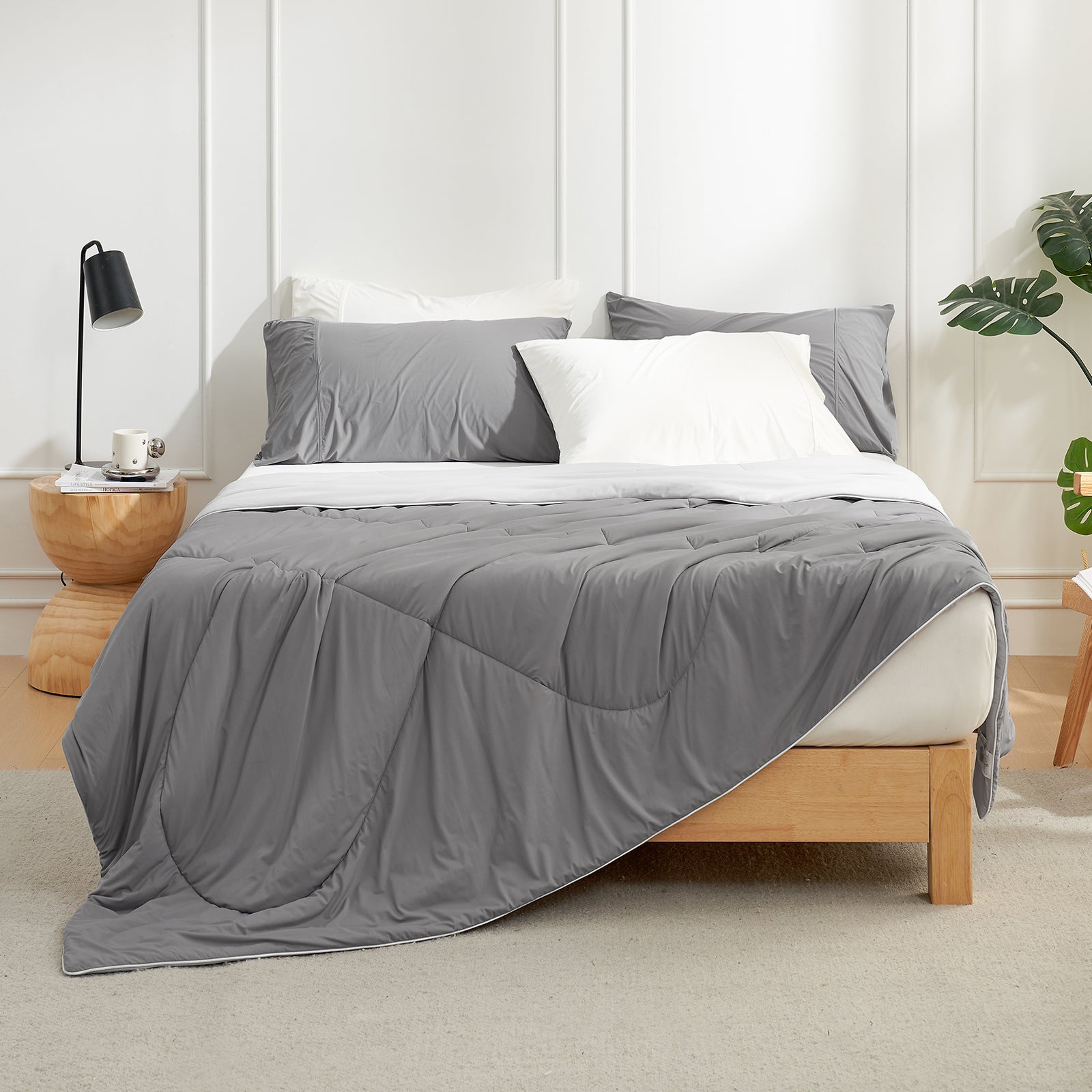Dark Grey Snuggle Sac comforter on a bed in a bedroom setting with a lamp and plant.#color_Dark Grey