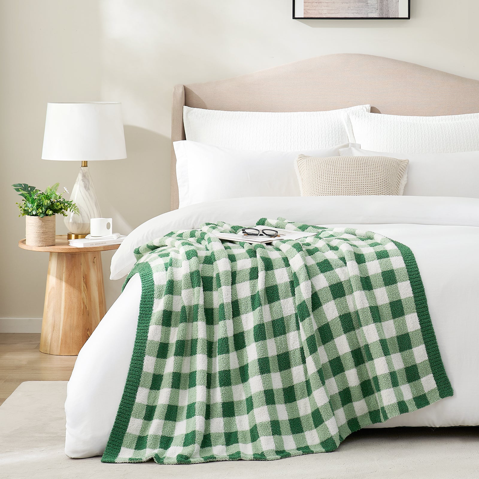 Green and white checkered blanket draped over a bed with glasses and magazine in a bright room with a vase of plants #color_Green