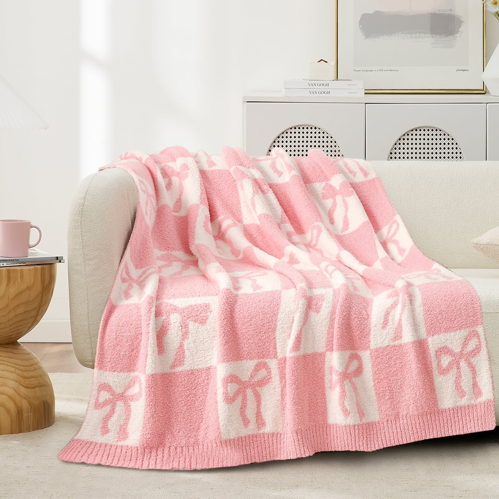Snuggle Sacs Reversible Checkered Bow Feather Yarn Knit Throw Blanket on a beige couch#color_Pink_Bow