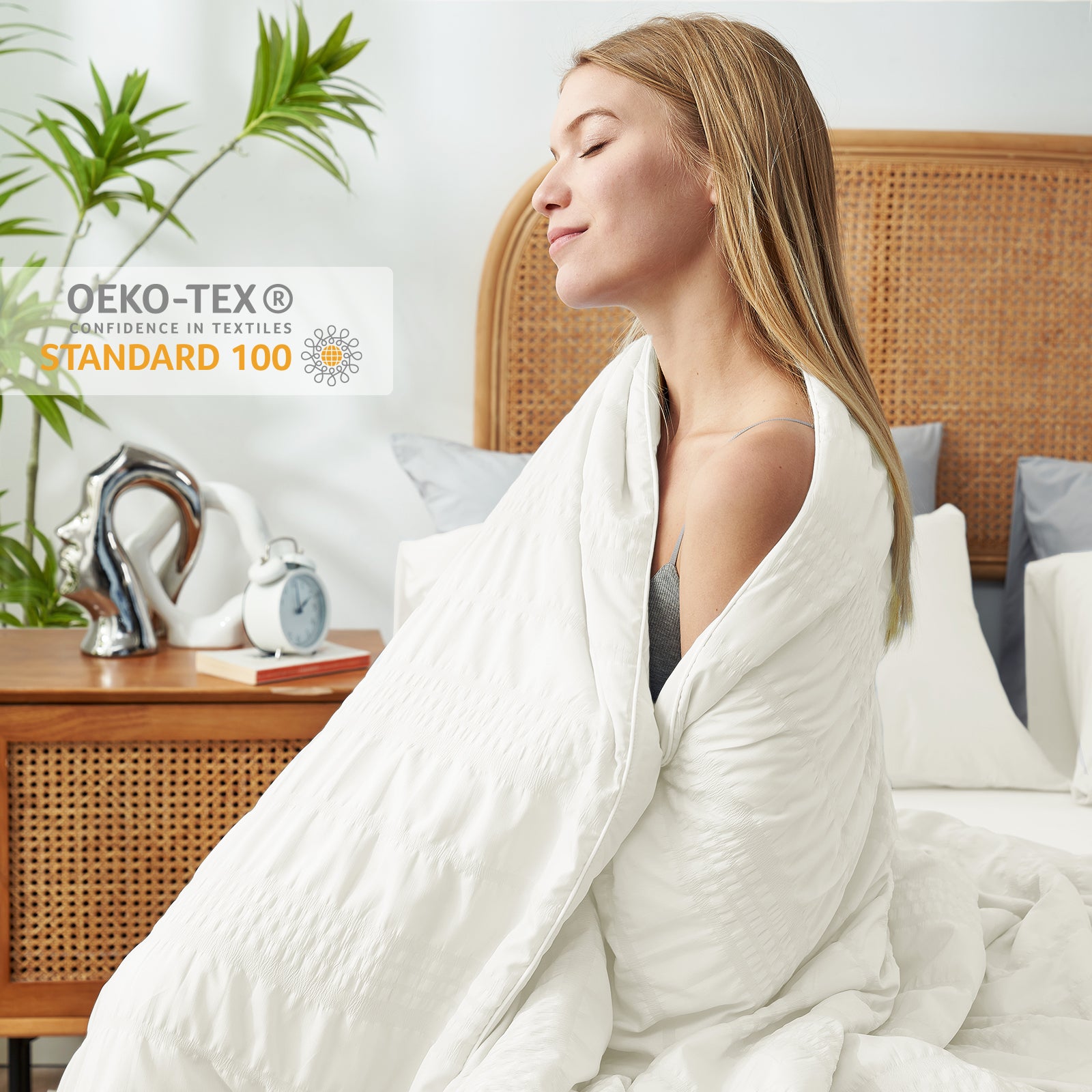 A woman wrapped in Snuggle Sac Cooling comforter sitting on the bed proving OEK0-TEX certificate #color_White