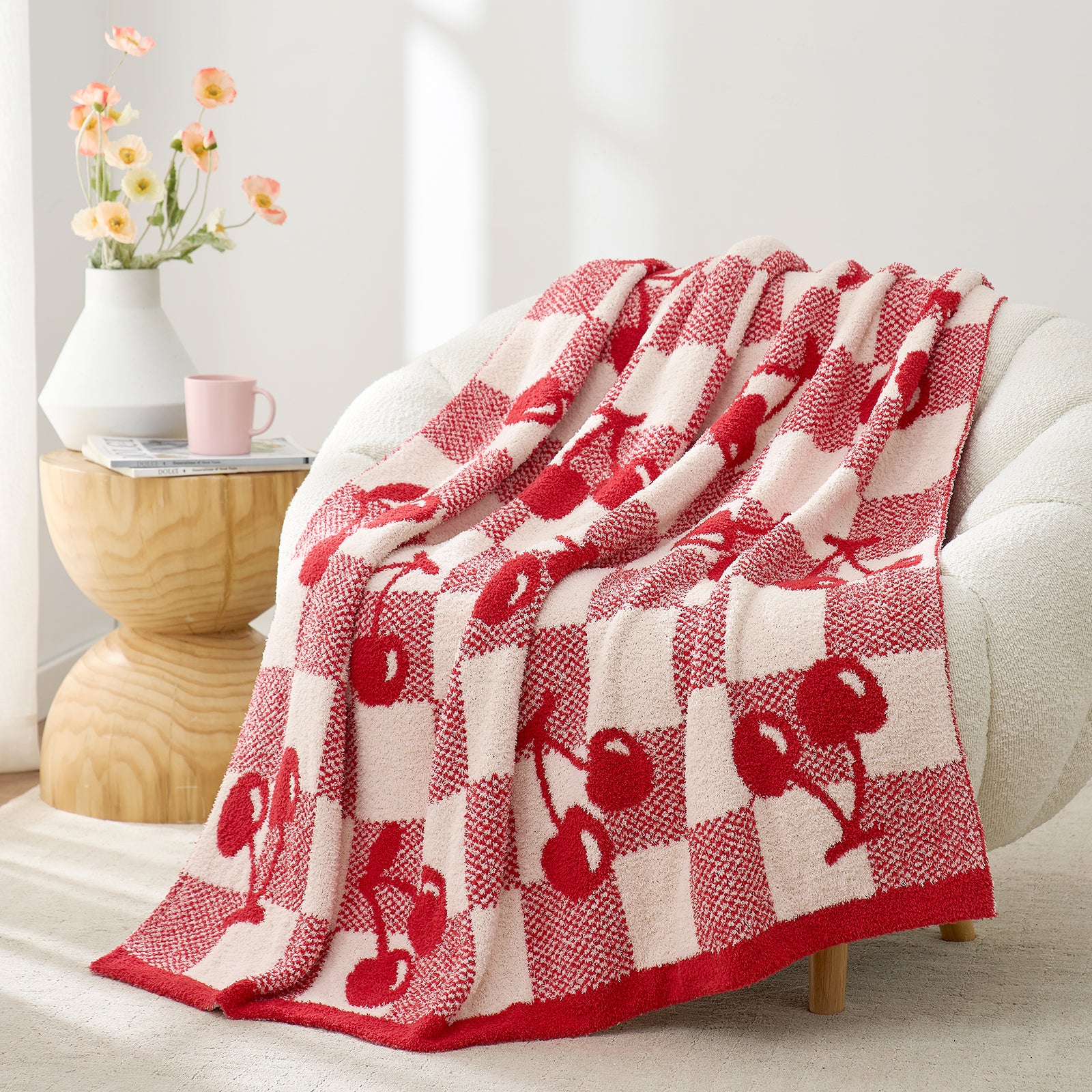 Snuggle Sacs Red Cherry Feather Yarn Knit Throw Blanket drapped on the grey couch with a vase of flower behind#color_Red_Cherry