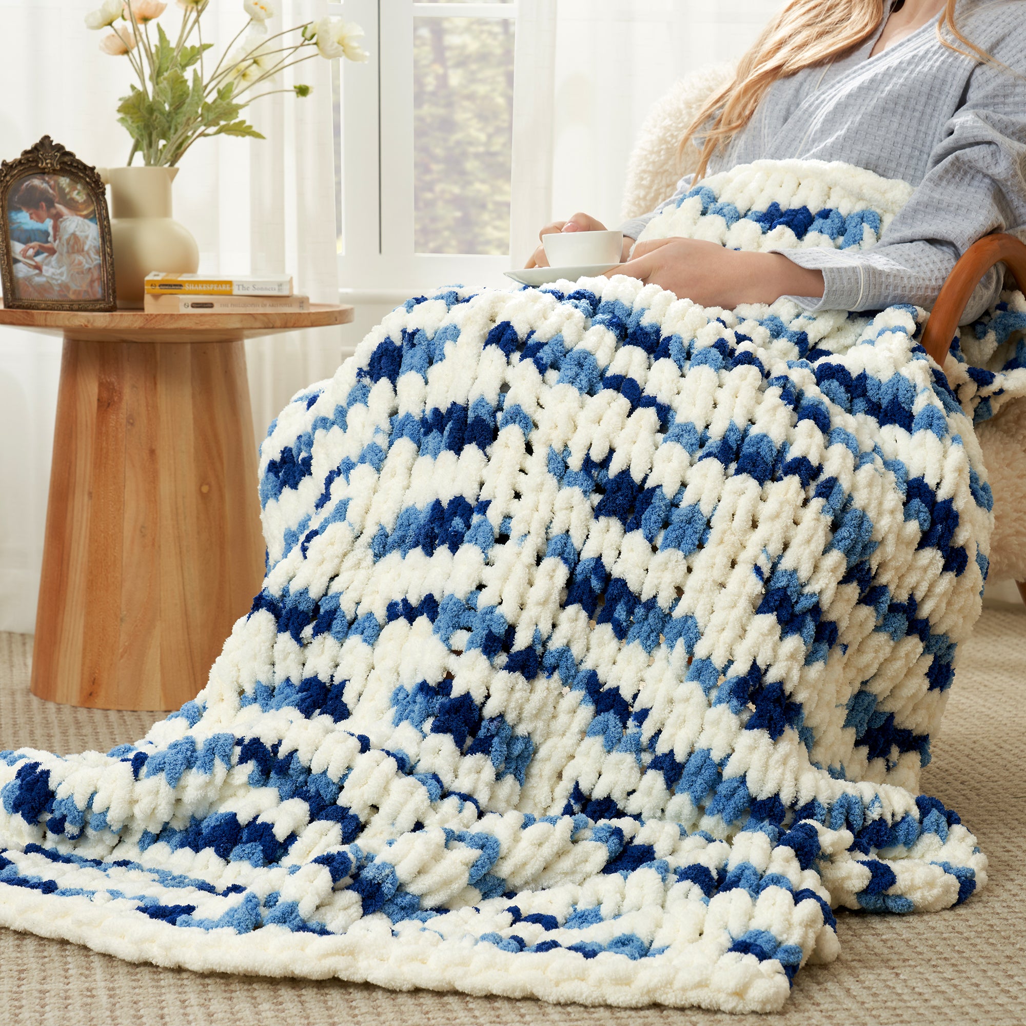 Woman relaxing with a handmade chunky chenille knit throw blanket in Blue Stripe #color_Blue Stripe