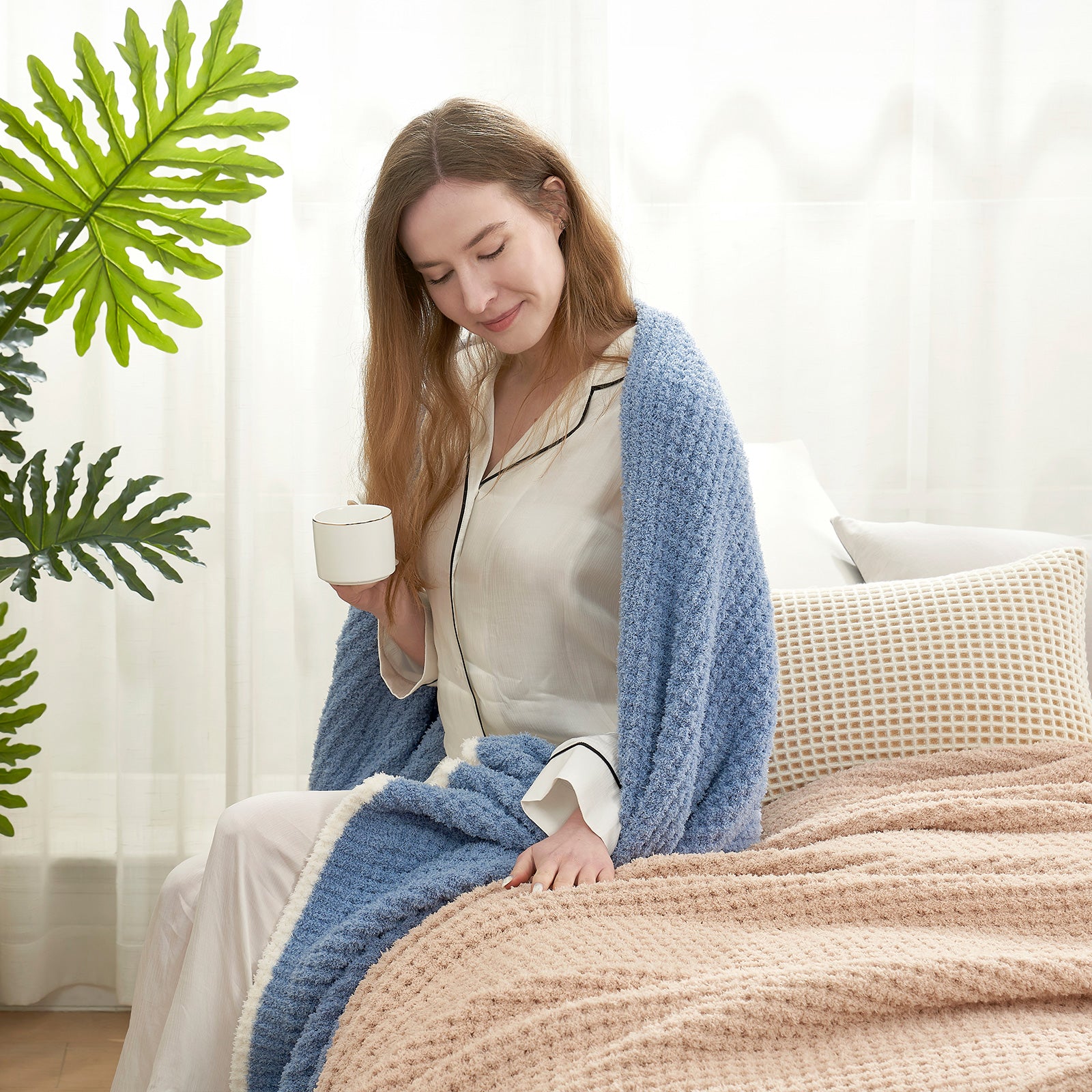 A woman wrapped with Soft Waffle Feather Yarn Knit Throw Blanket sitting on the bed with a mug#Color_Blue