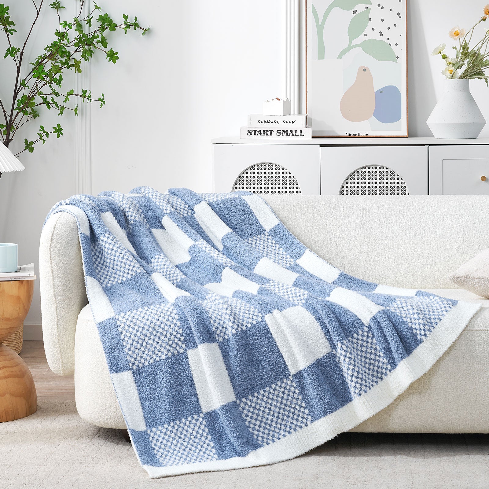 Blue and white checkered blanket draped over a sofa in a living room setting. #color_Pale Blue
