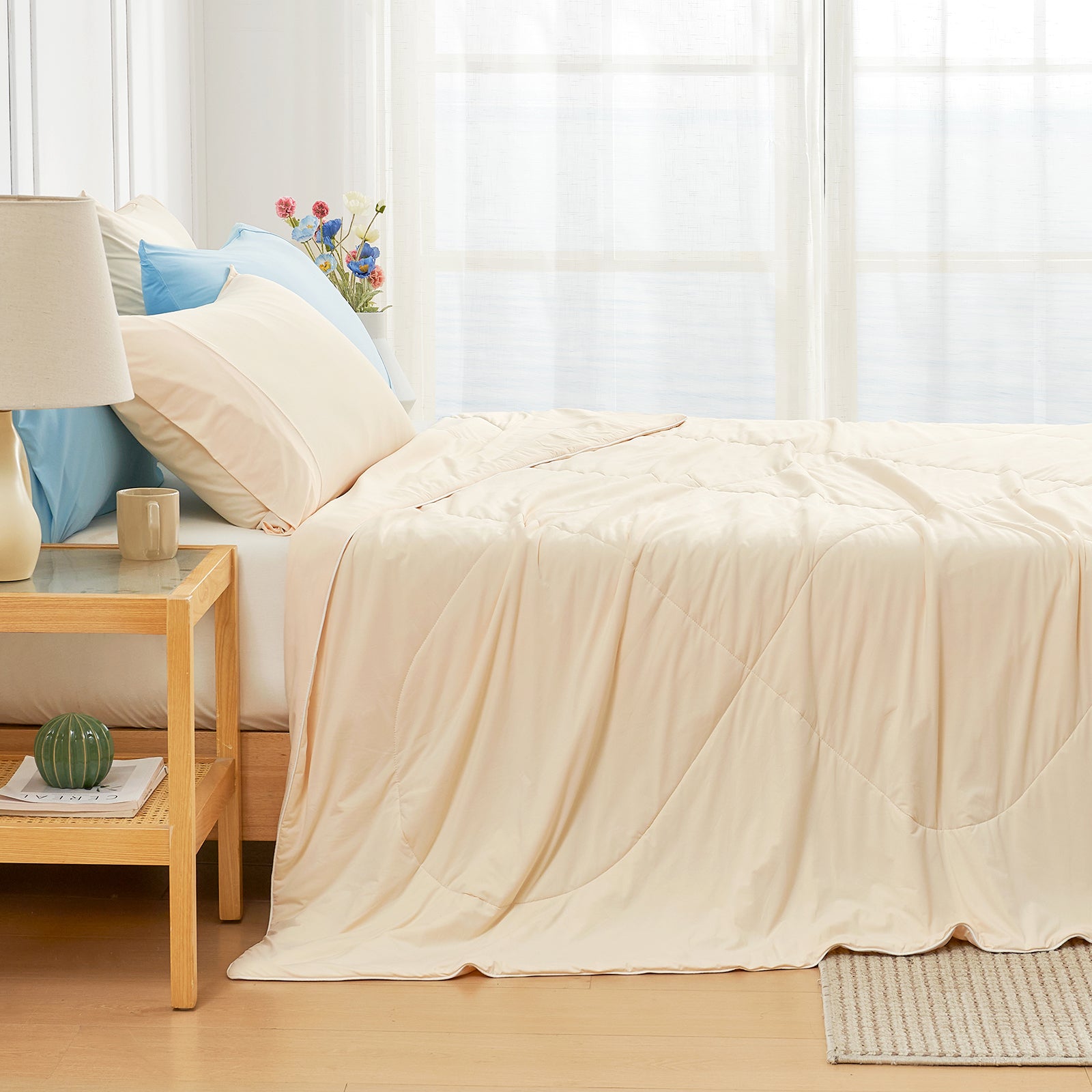 Left side view of Snuggle Sac yellow comforter on a bed with pillows and a table in a bright room.#color_Yellow