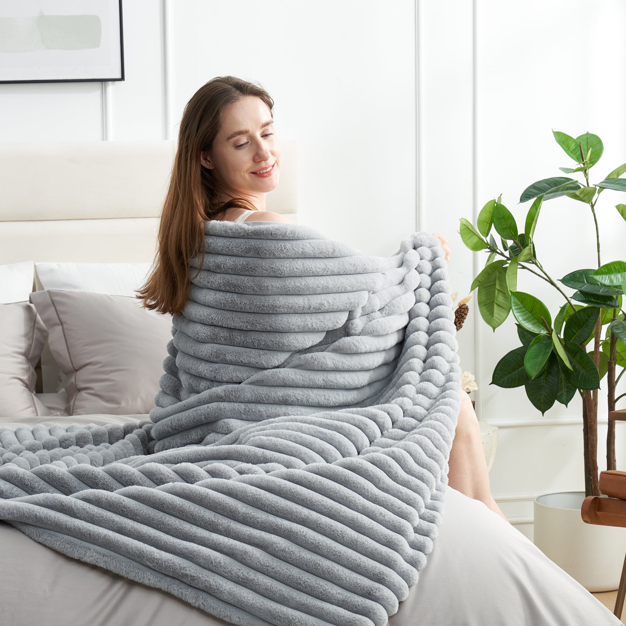 Woman relaxing on bed with a striped faux fur throw blanket in Light Grey #color_Light Grey