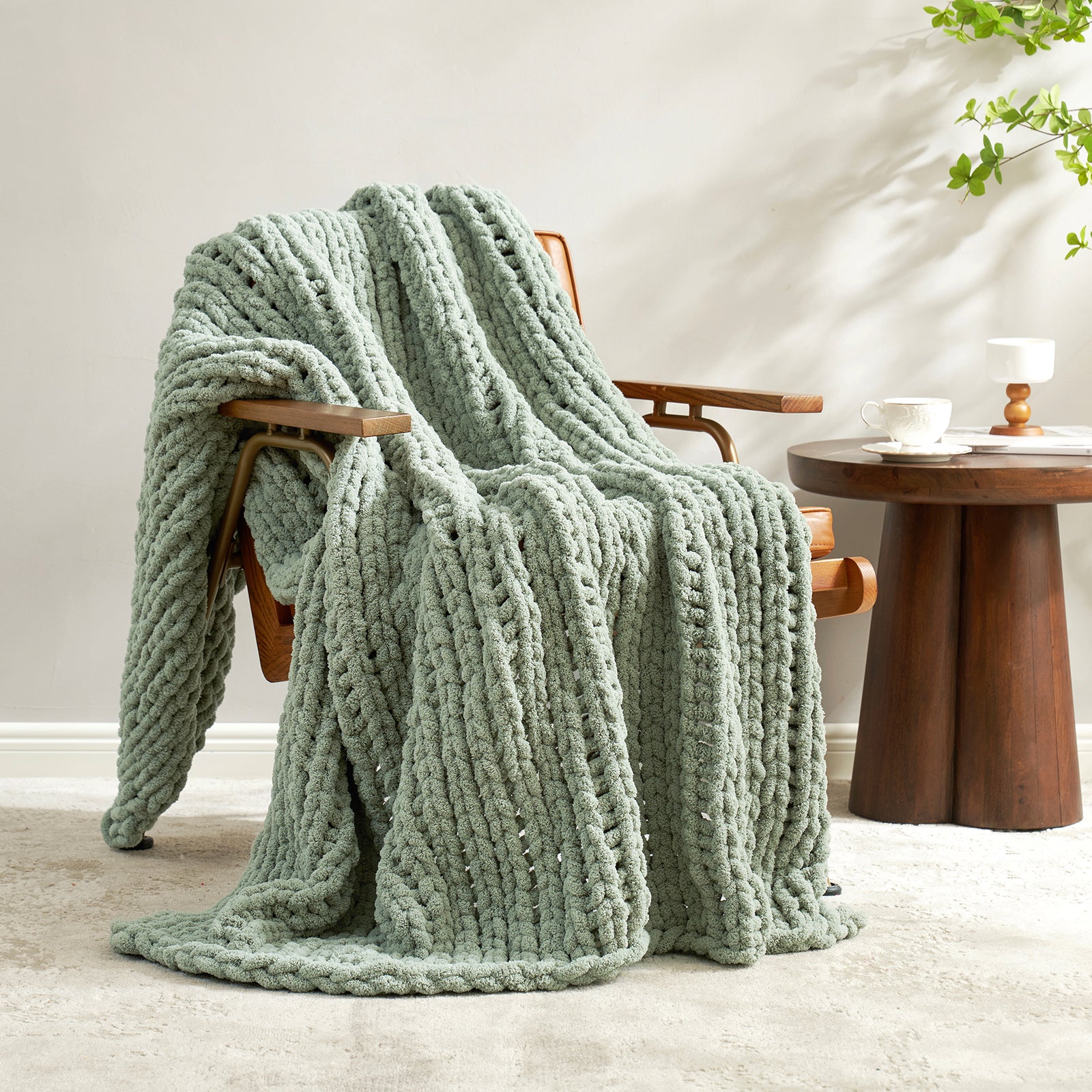 Snuggle Sac chunky knit throw blanket in Sage Green draped over a chair in a cozy living space #color_Sage Green