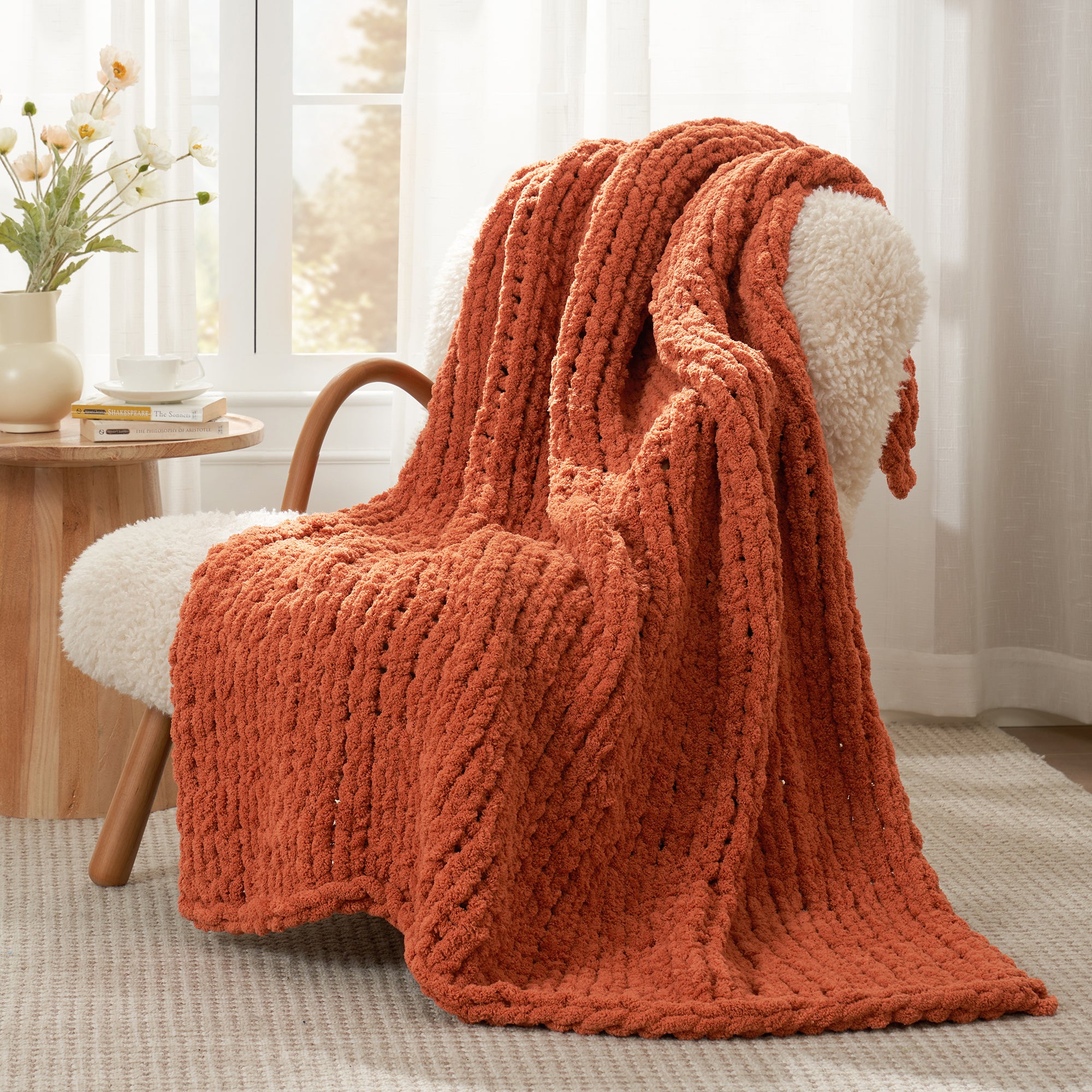 Snuggle Sac chunky knit throw blanket in Burnt Orange draped over a chair in a cozy living space #color_Burnt Orange