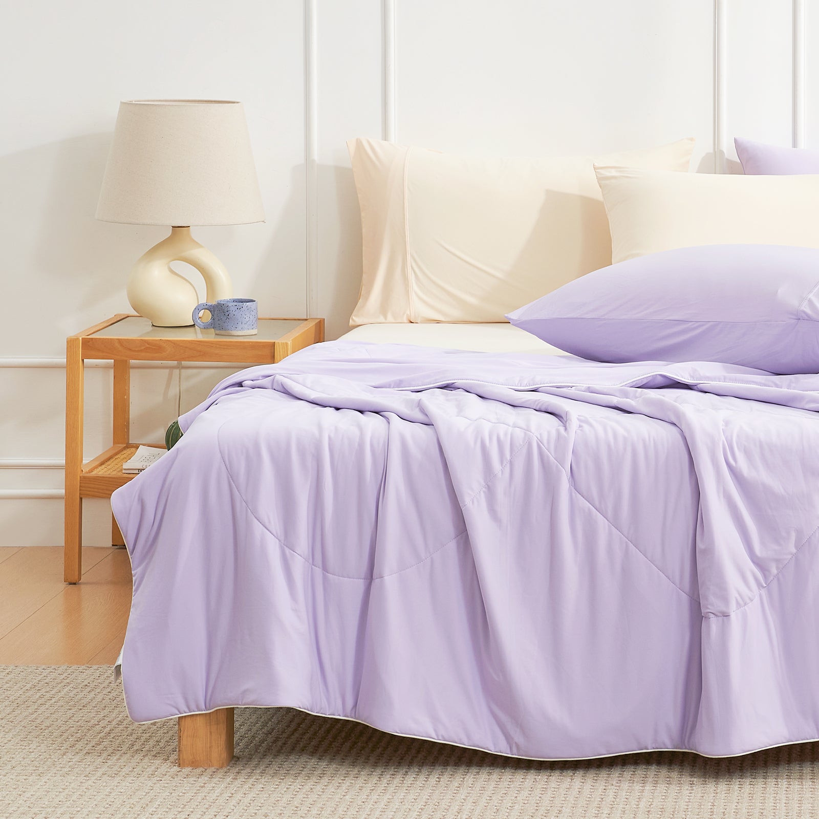 Bed with purple Snuggle Sac cooling comforter and pillows in a bedroom setting.#color_Purple