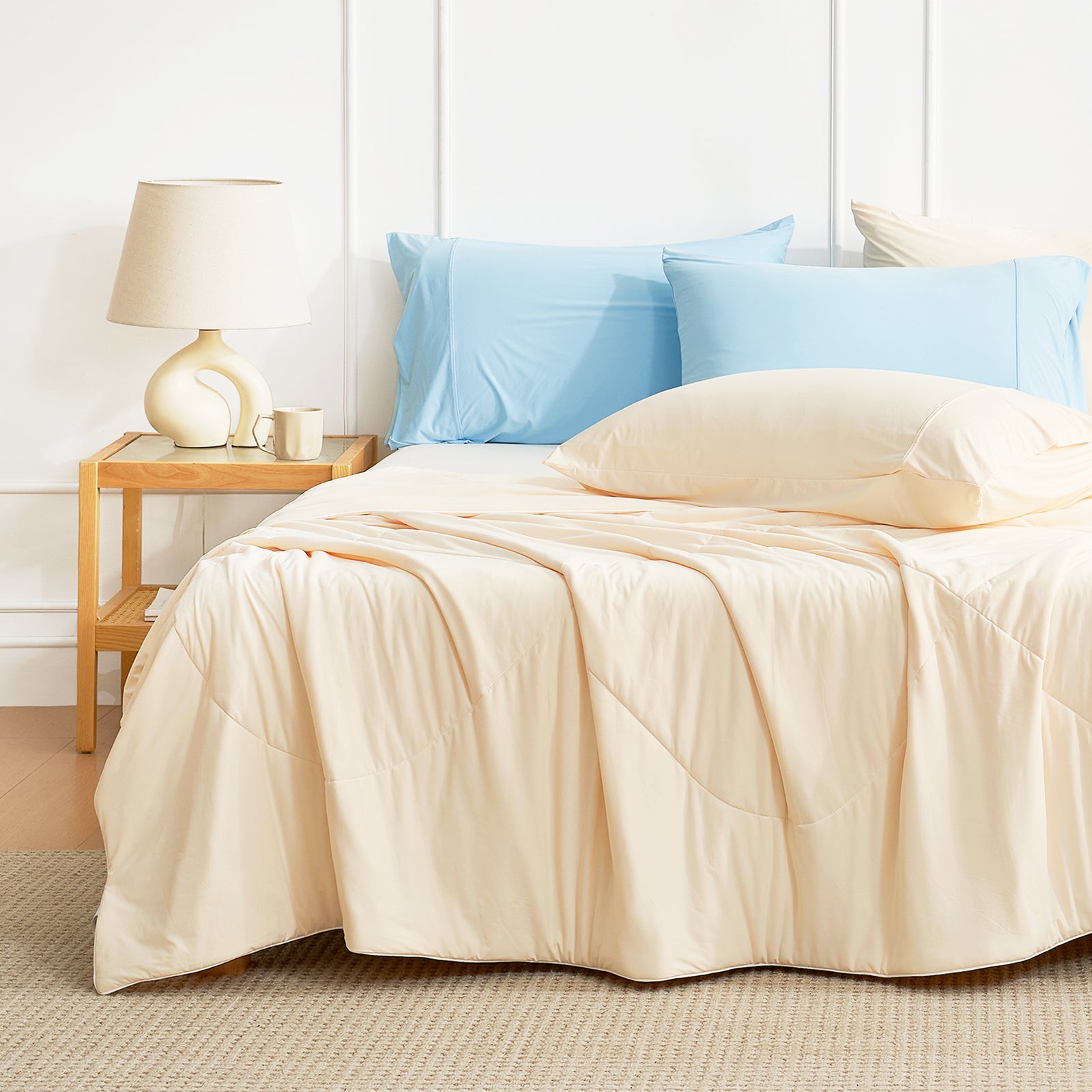 Neatly made bed with Snuggle Sac cooling comforter and pillows in a bedroom setting in yellow.#color_Yellow