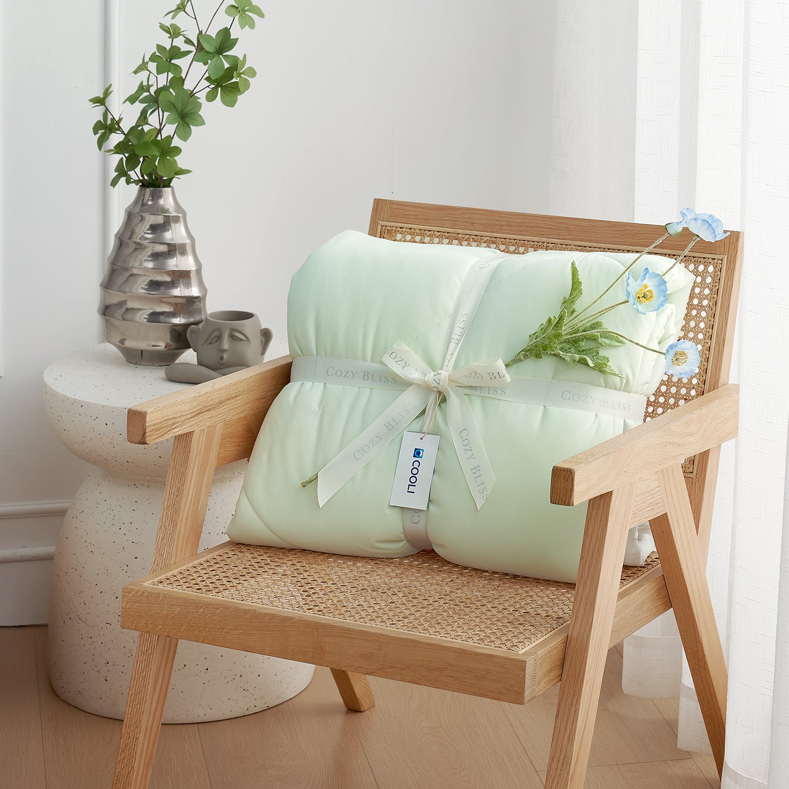 Snuggle Sac Cooling comforter with a white ribbon on a wooden chair, perfect as gift.#color_Mint Green