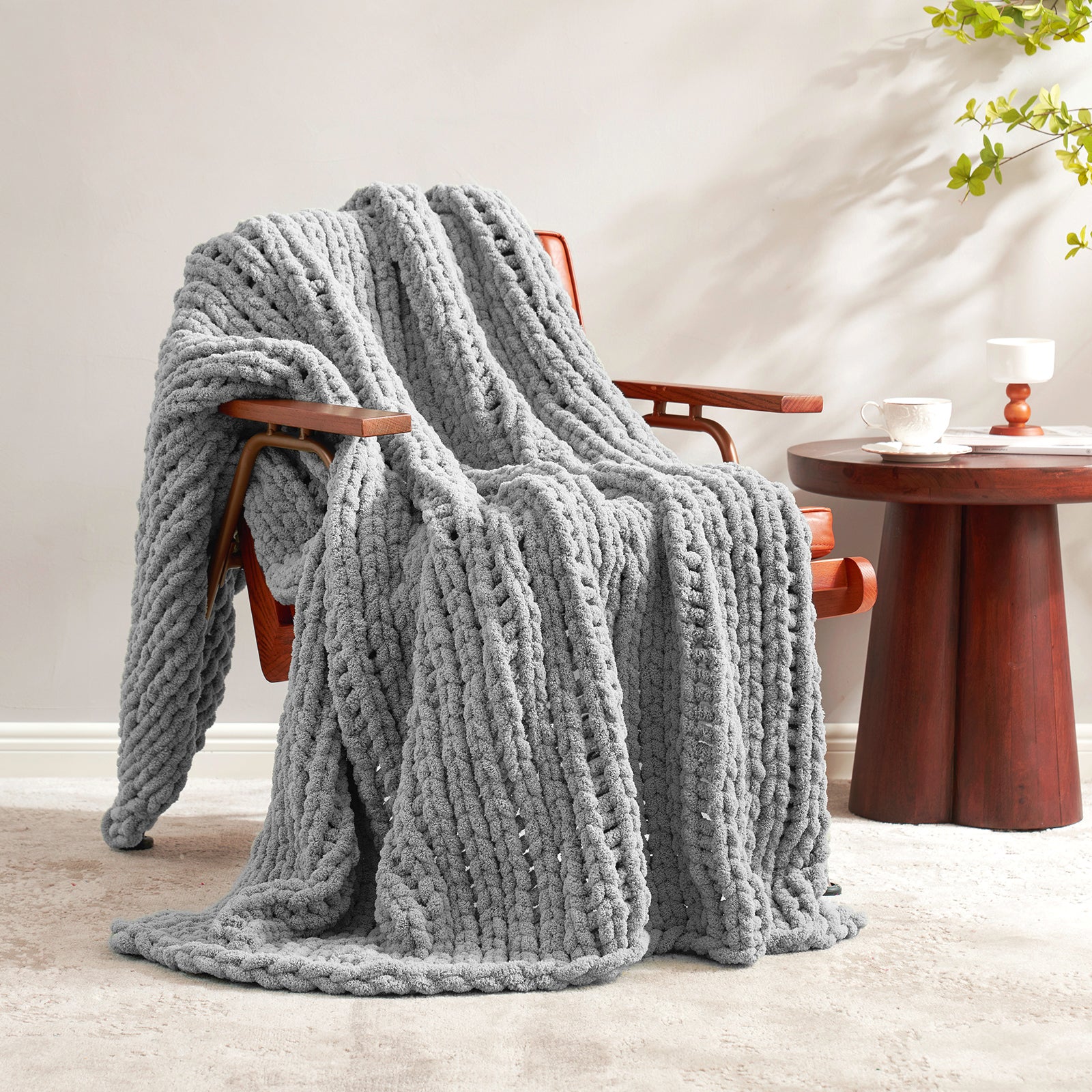 Snuggle Sac chunky knit throw blanket in Light Grey draped over a chair in a cozy living space #color_Light Grey