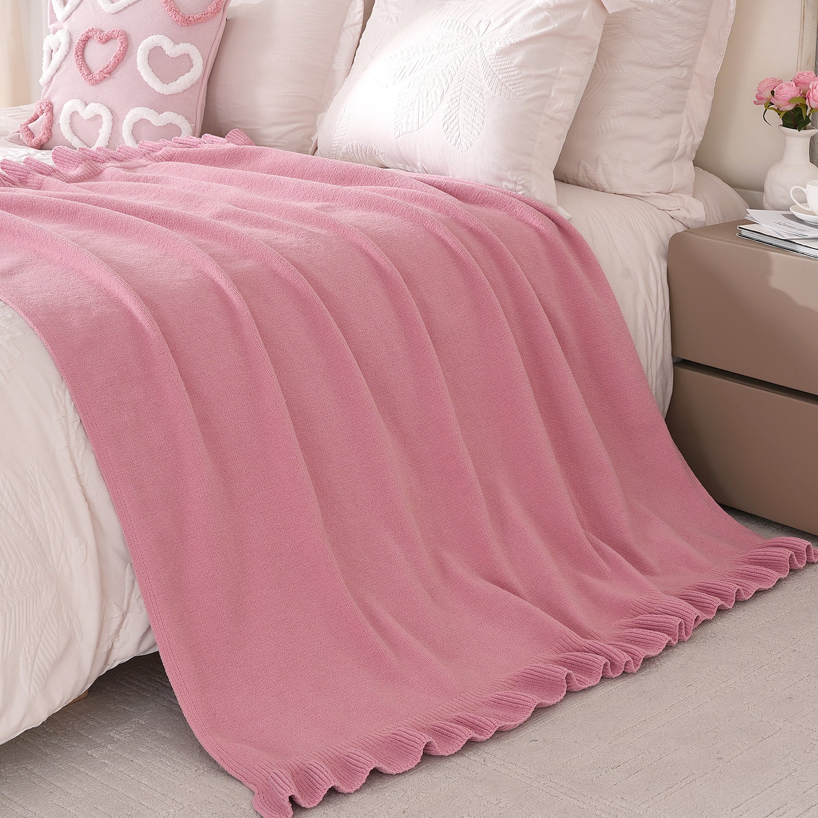 Ruffle chenille knit throw blanket in Pink placed at the end of a bed, adding softness and decorative texture #color_Pink