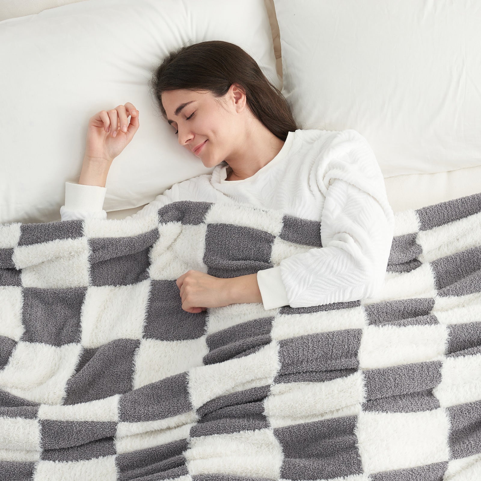 A woman laying down on the bed under UltraCozy Checkered Feather Yarn Knit Throw Blanket#Color_Grey White