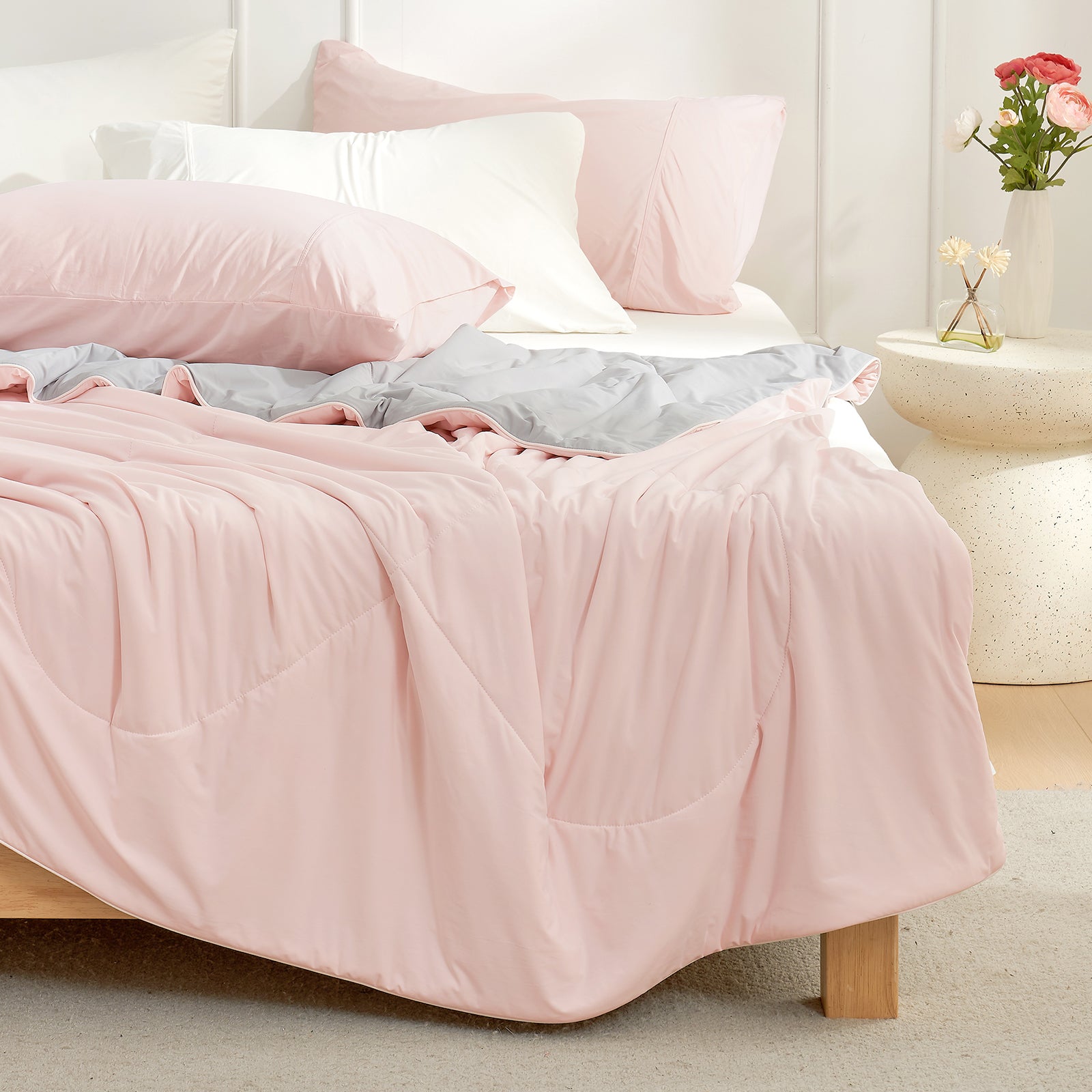 Bed with pink Snuggle Sac cooling comforter and pillows in a bedroom setting#color_Pink/Grey