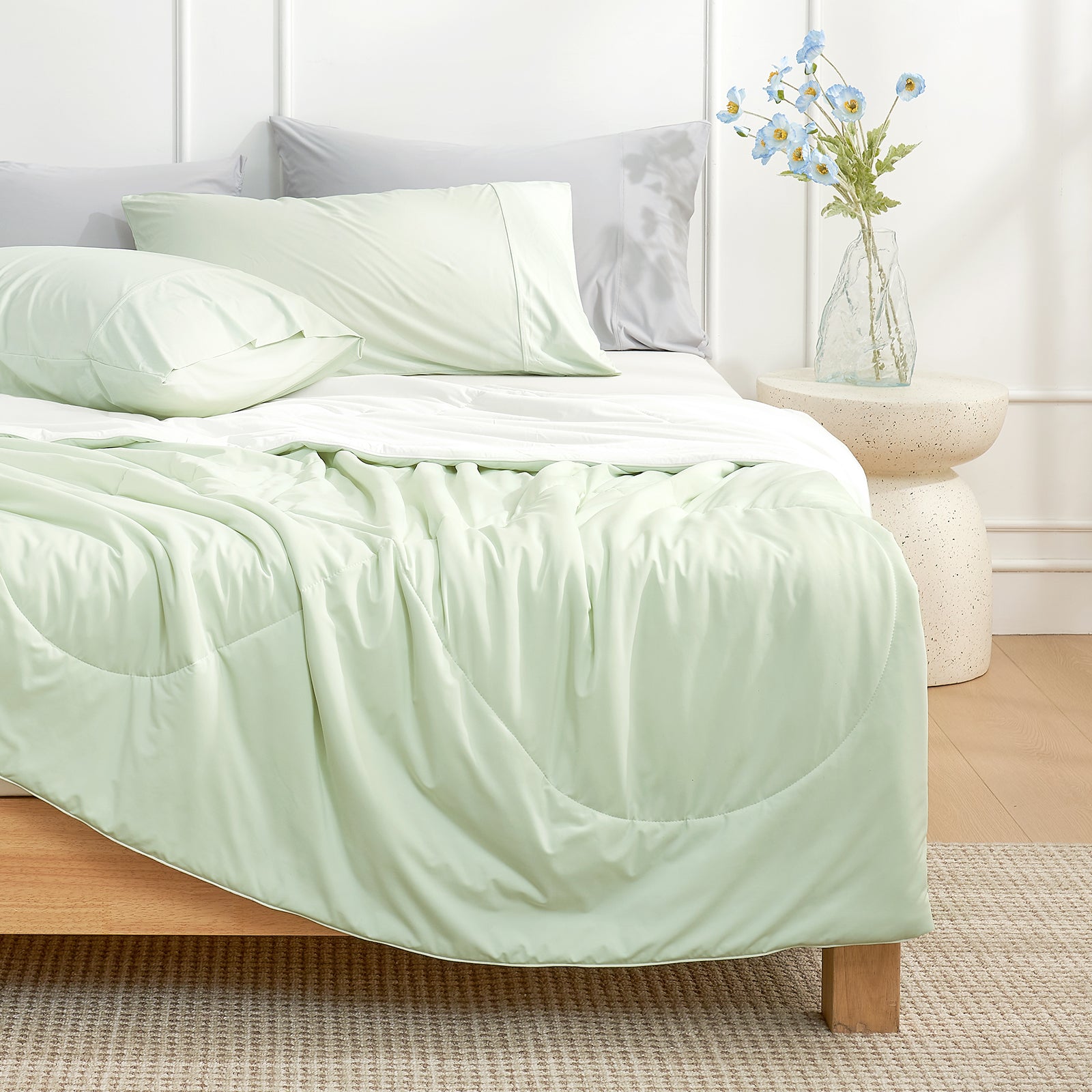 Bed with mint green Snuggle Sac cooling comforter and pillows in a bedroom setting.#color_Mint Green