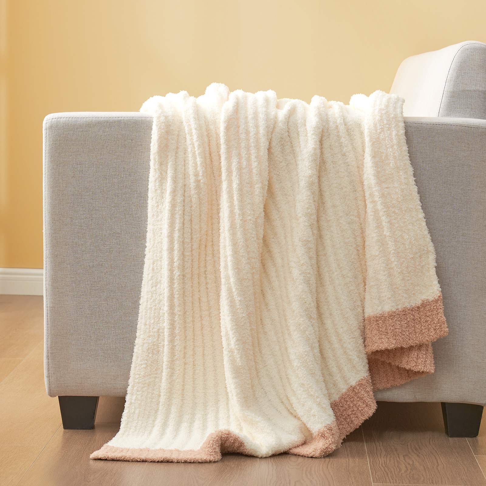 Snuggle Sac UltraSoft Ribbed Feather Yarn Knit Throw Blanket draped on the grey couch#Color_Cream