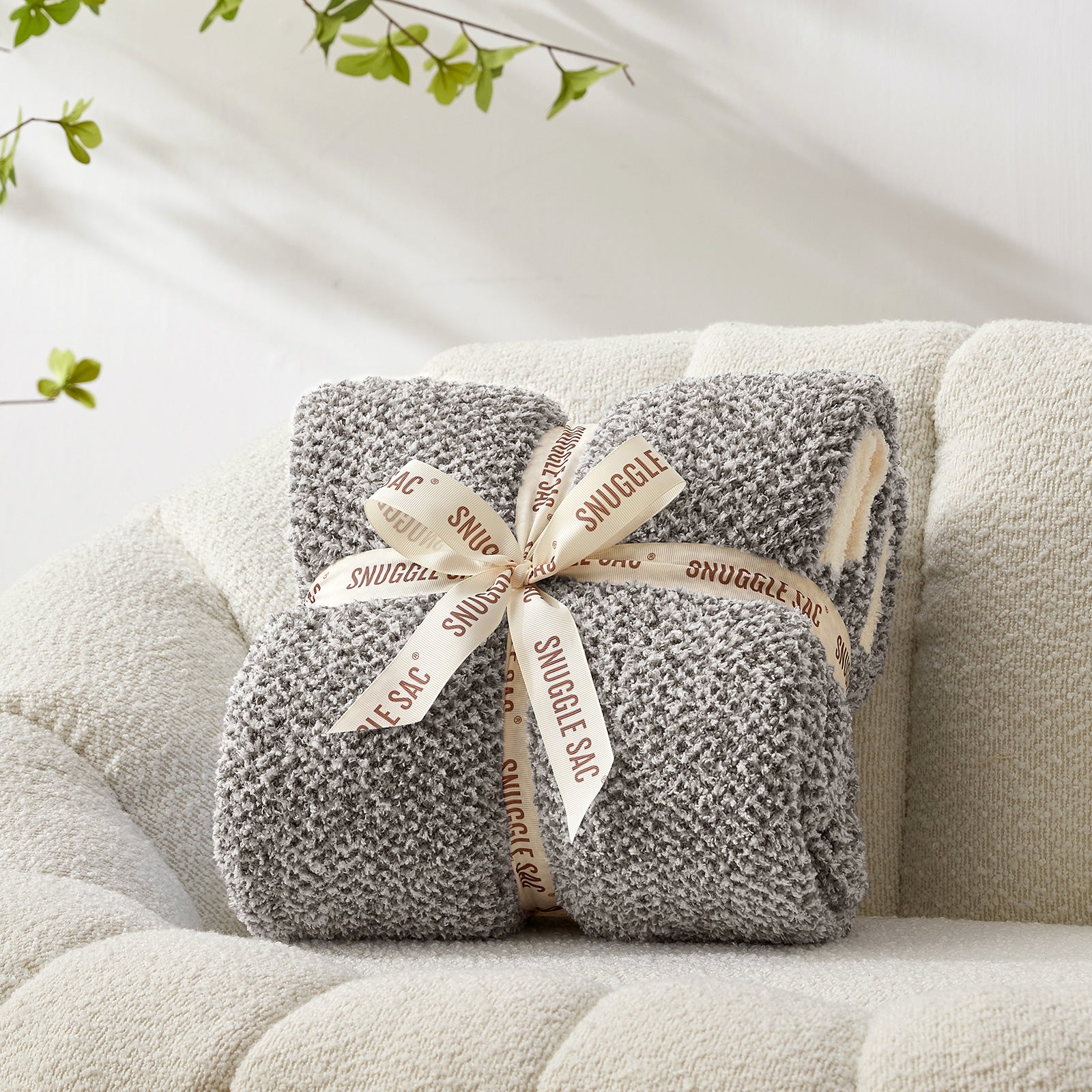 Gray plush blanket with a decorative bow on a beige couch #color_Dark Grey