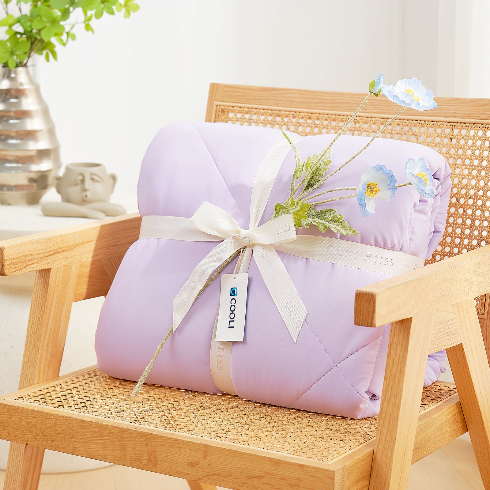 Snuggle Sac Cooling comforter with a white ribbon on a wooden chair, perfect as gift.#color_Purple
