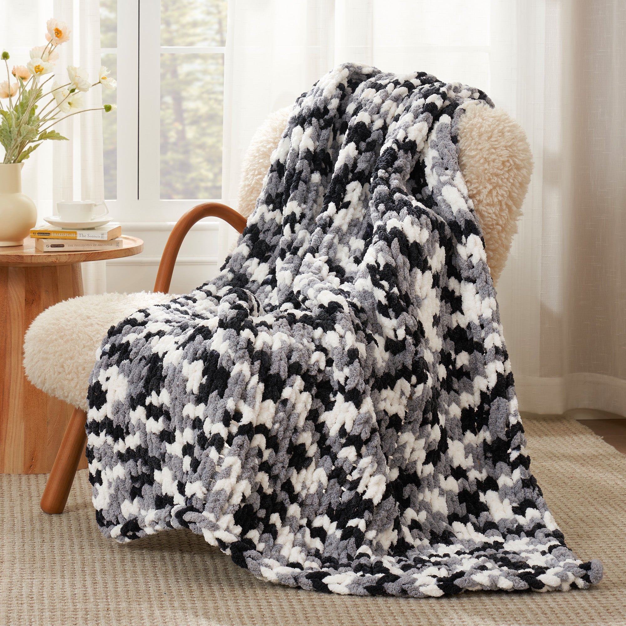 Snuggle Sac chunky chenille knit throw blanket in Black draped over a chair creating a cozy corner #color_Black