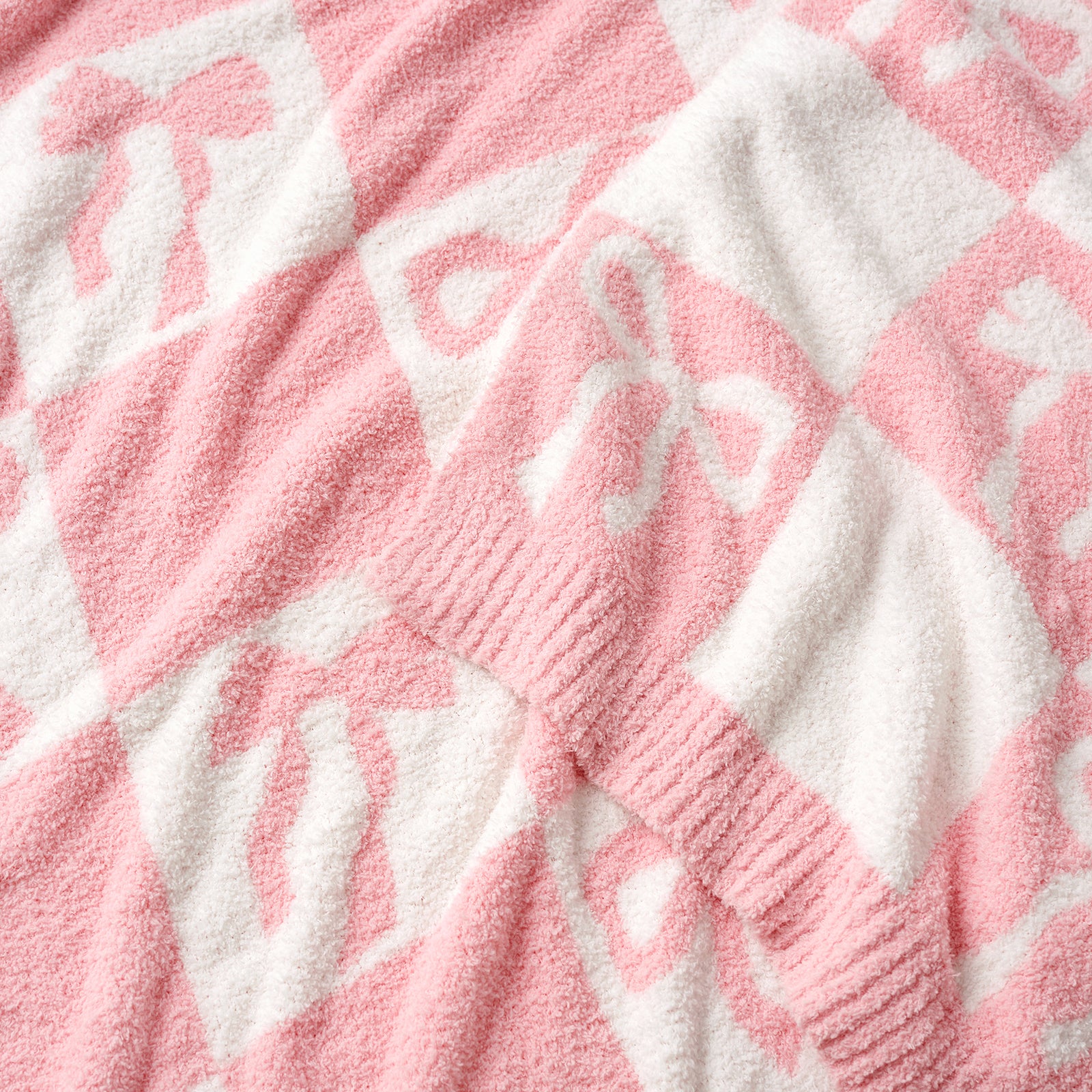 Close up of Snuggle Sacs Reversible Checkered Bow Feather Yarn Knit Throw Blanket #color_Pink_Bow