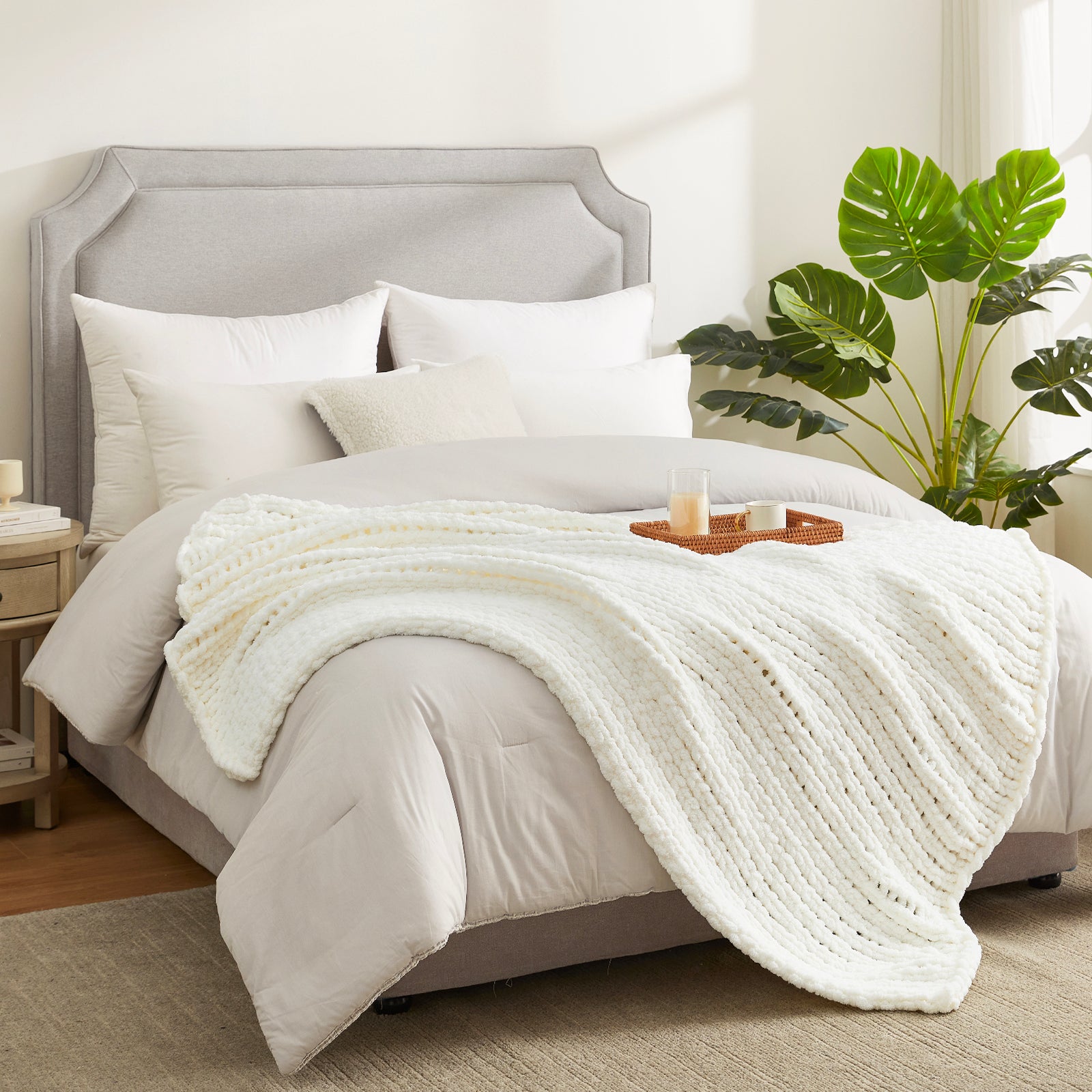 Soft chunky knit throw blanket in Ivory layered on bed in a modern bedroom setting #color_Ivory