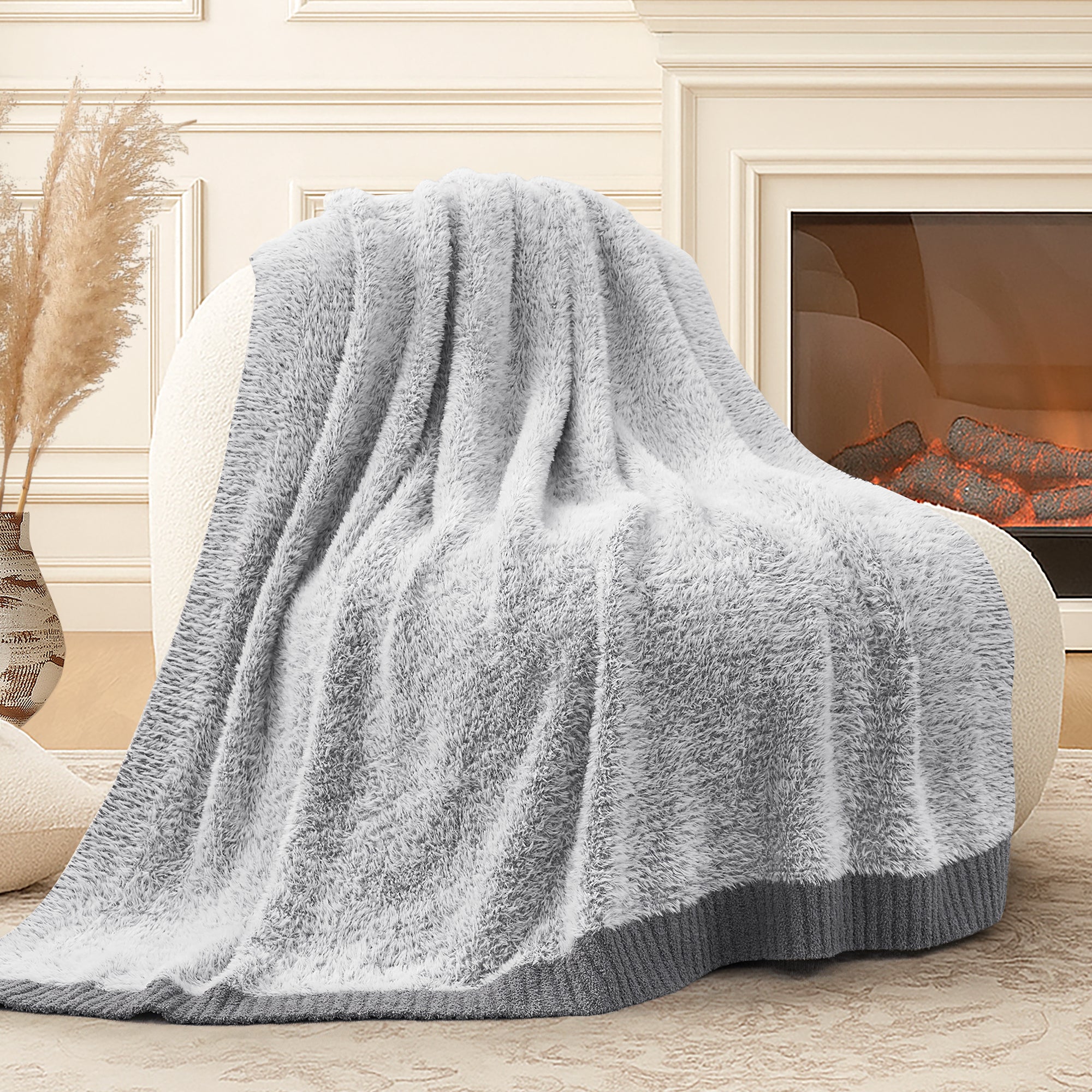 Snuggle Sac ultrasoft faux fur knit throw blanket in Gray draped over a sofa near a fireplace, creating a warm and cozy atmosphere #color_Gray