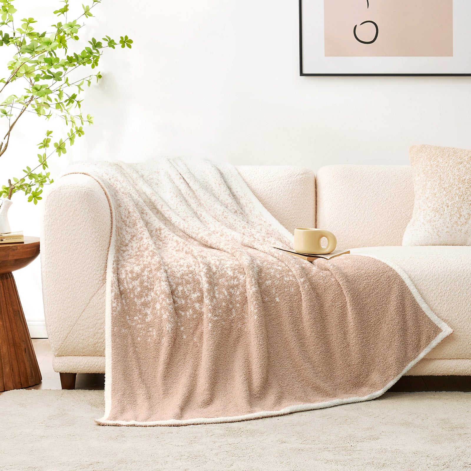 Snuggle Sacs Reversible Ombre Heather Feather Yarn Knit Throw Blanket on a beige couch with a book and mug #color_Khaki