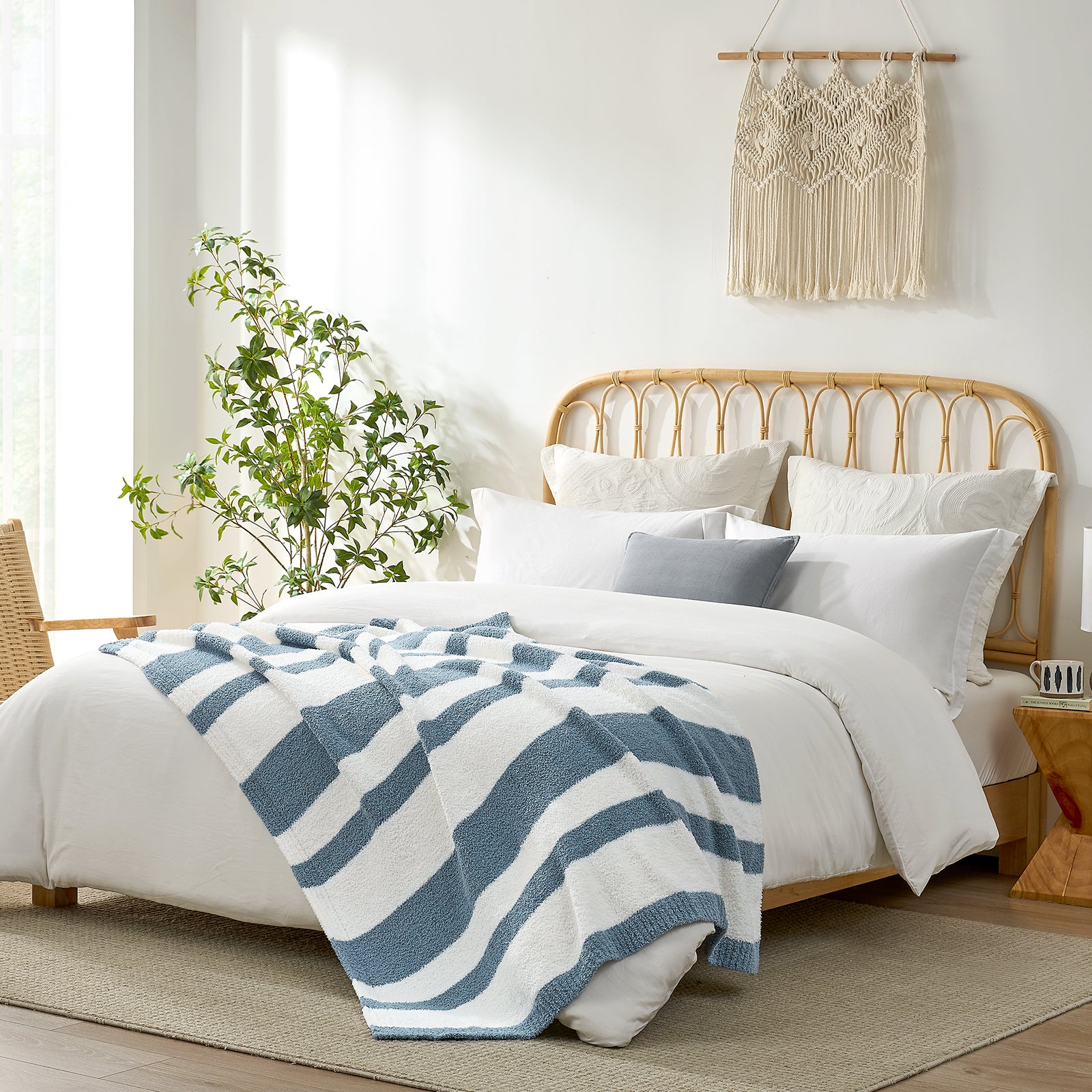 Snuggle Sacs Reversible Blue Striped Feather Yarn Knit Throw Blanket on the bed in a bright room with plants and decorations#color_Blue