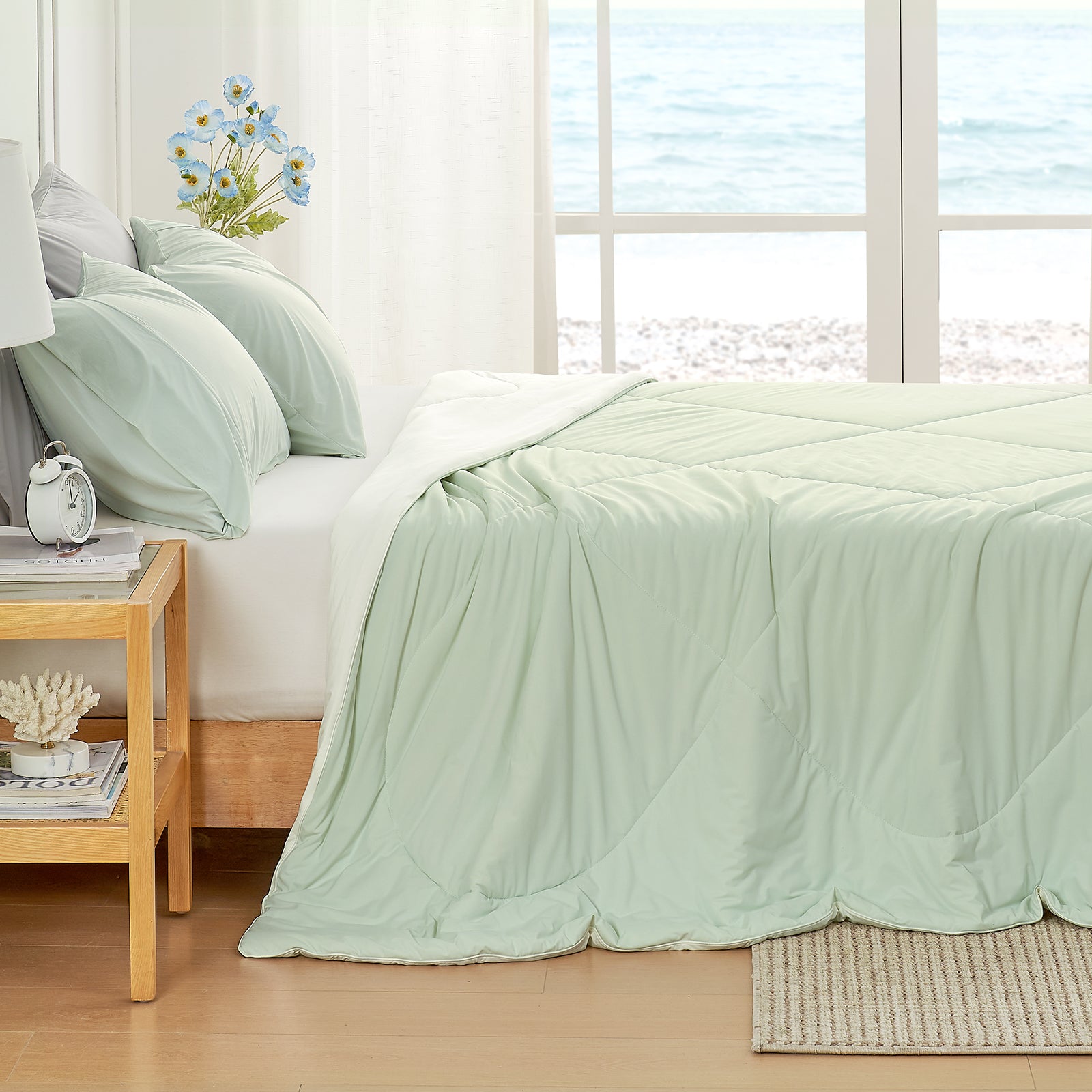 Left side view of mint green Snuggle Sac comforter on a bed in a bright bedroom with large windows.#color_Mint Green