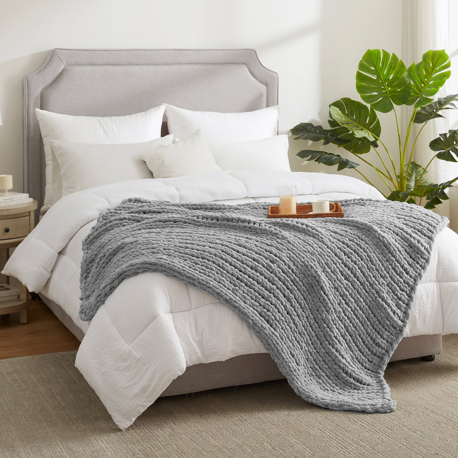 Chunky knit throw blanket in Light Grey layered on a bed in a modern bedroom setting #color_Light Grey