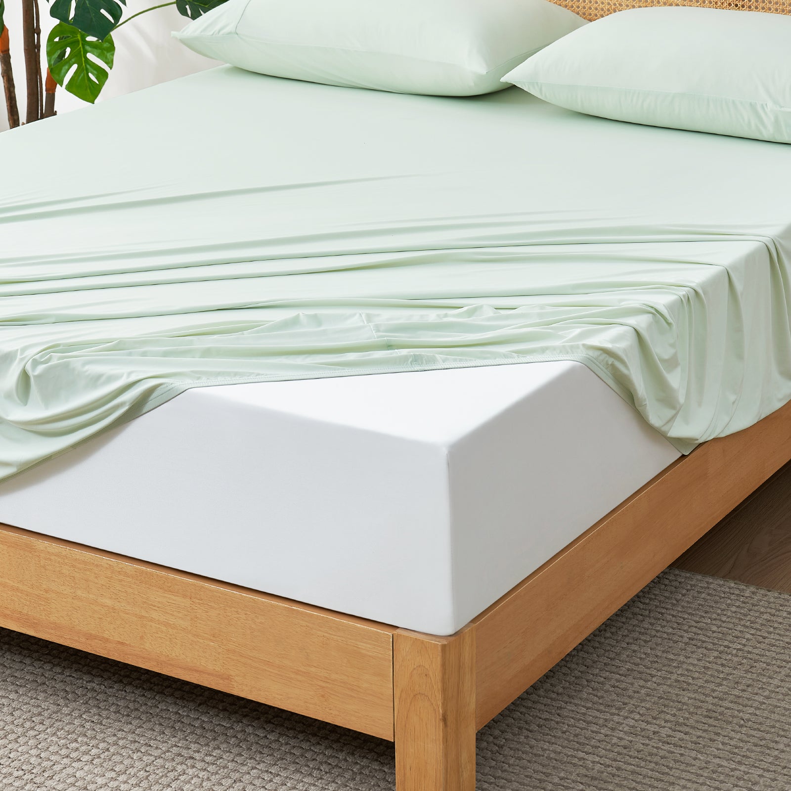 Mint Green Snuggle Sac fitted sheet set on wooden bed.#color_Mint Green