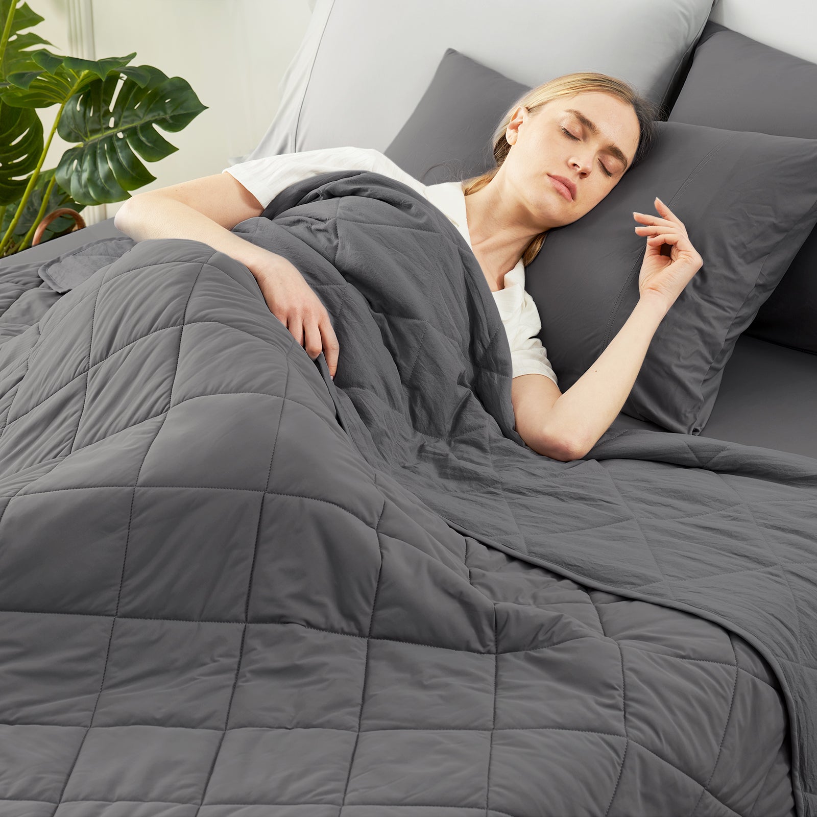 Woman sleeping under a Snuggle Sac charcoal grey comforter in a cozy bedroom setting.   #color_Charcoal Grey