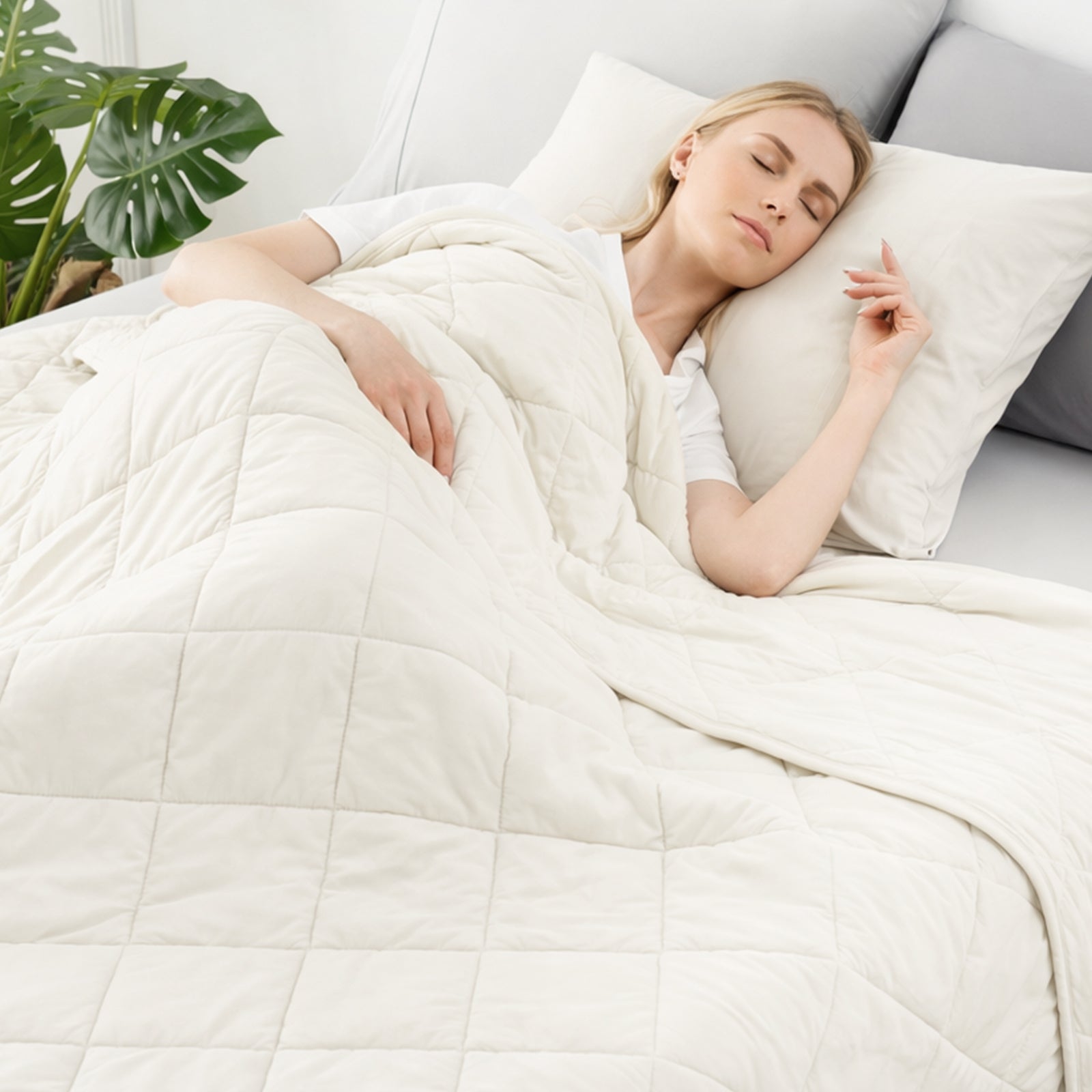 Woman sleeping under a Snuggle Sac white comforter in a cozy bedroom setting.   #color_White