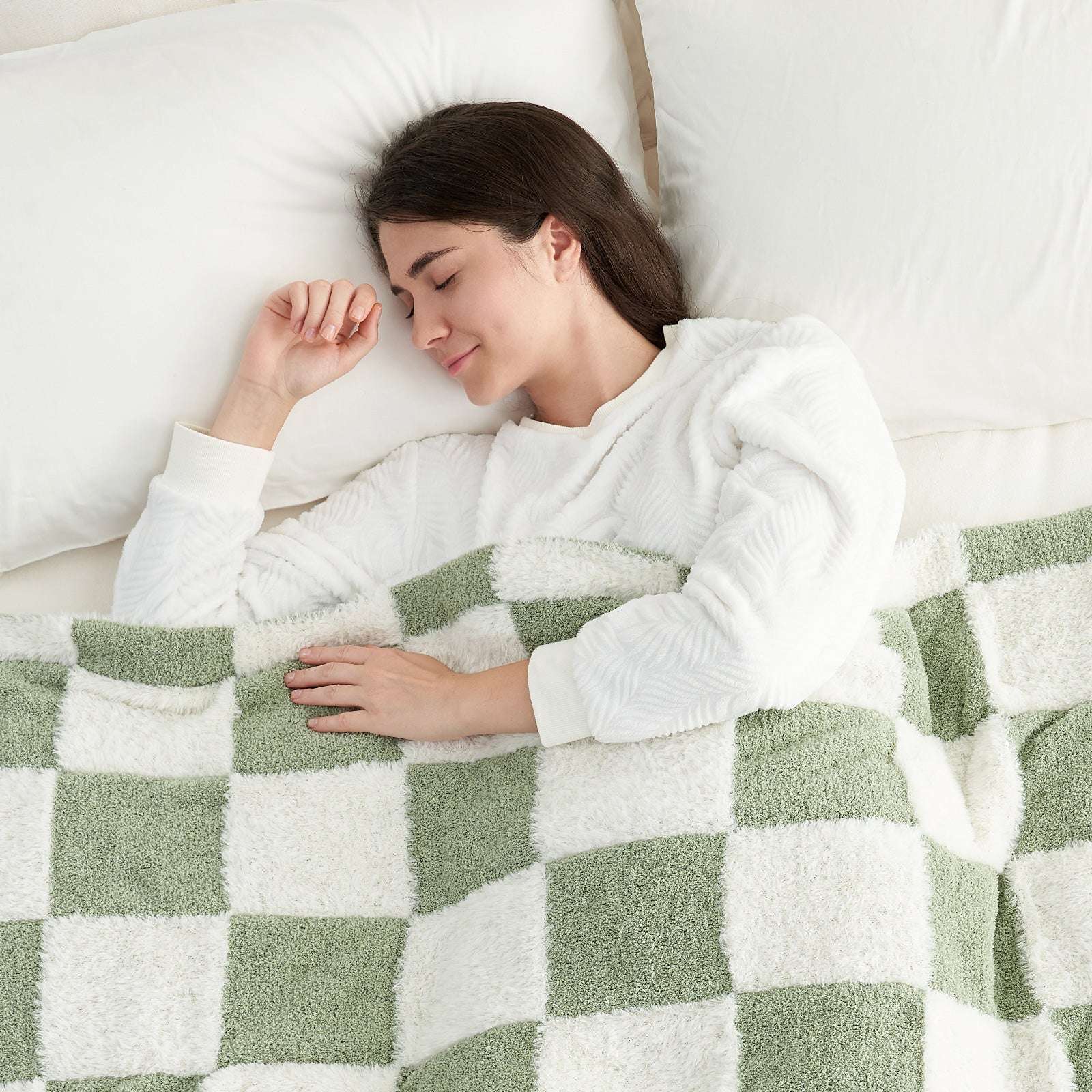 A woman laying down on the bed under UltraCozy Checkered Feather Yarn Knit Throw Blanket#Color_Sage Green White