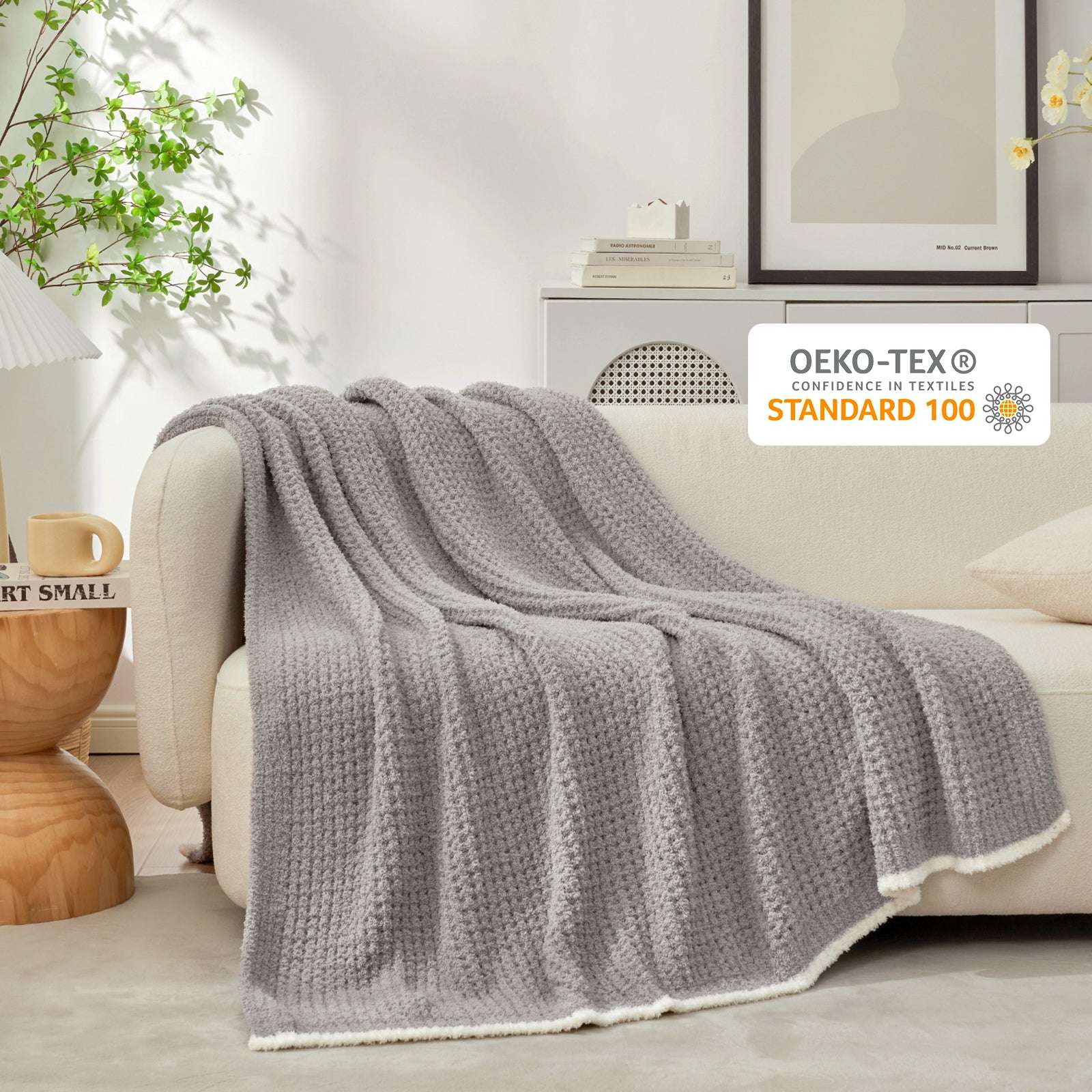 Soft Waffle Feather Yarn Knit Throw Blanket on a beige couch with vase of plant and mug#Color_Grey