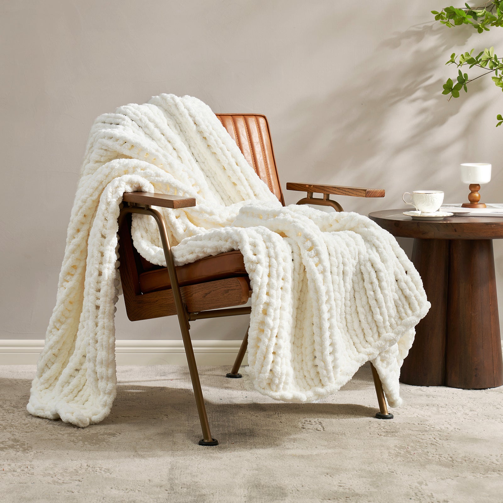 Snuggle Sac chunky knit throw blanket in Ivory draped over a chair in a cozy living space #color_Ivory