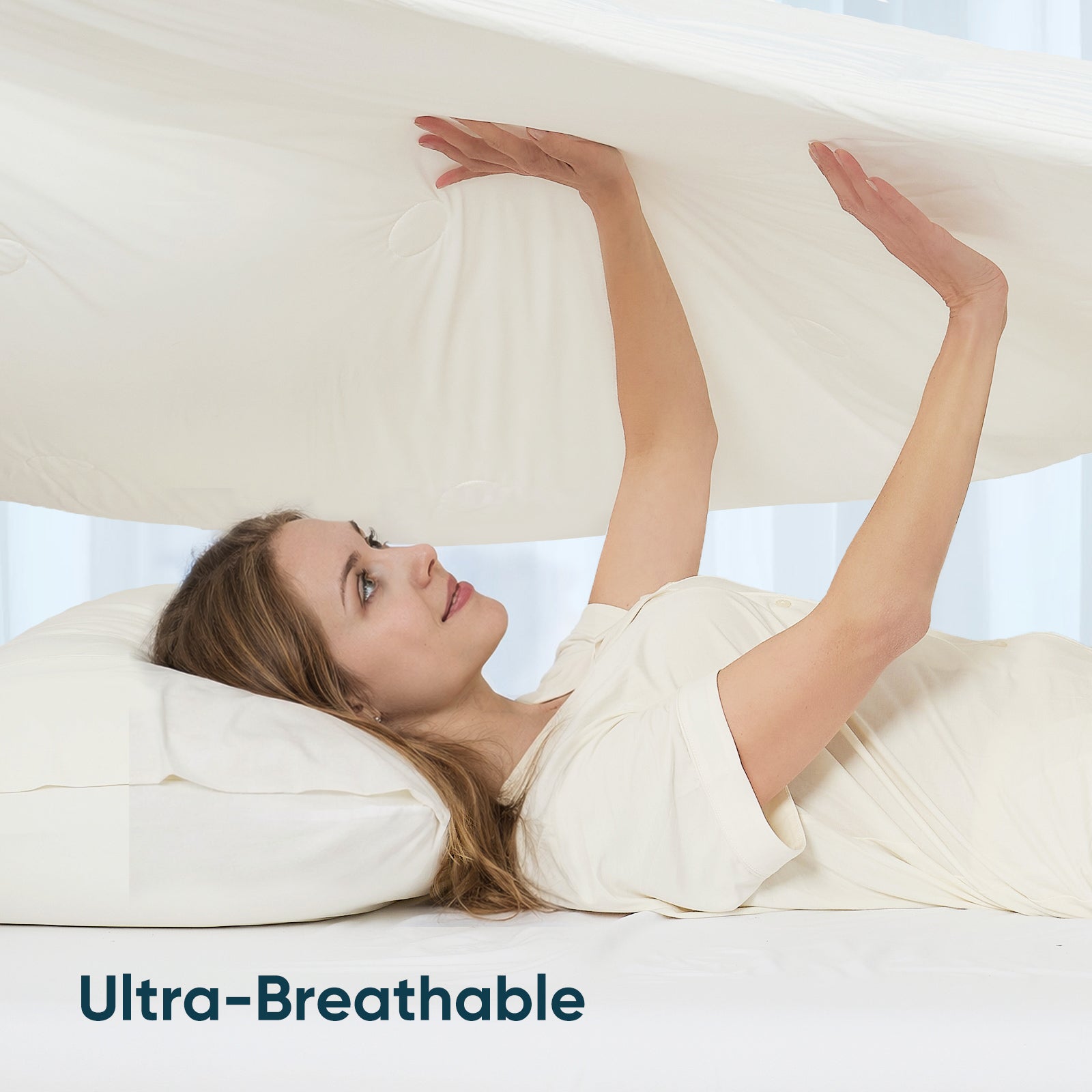 A woman laying down on the bed holding on Snuggle Sac Cooling comforter showing ultra breathable#color_White