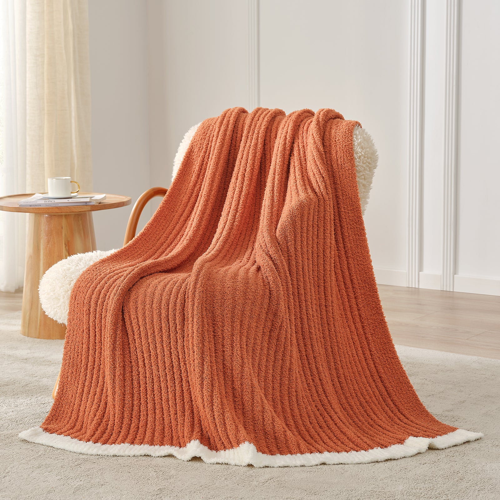 Snuggle Sac UltraSoft Ribbed Feather Yarn Knit Throw Blanket draped on the chair with a vase of flower#color_Burnt Orange