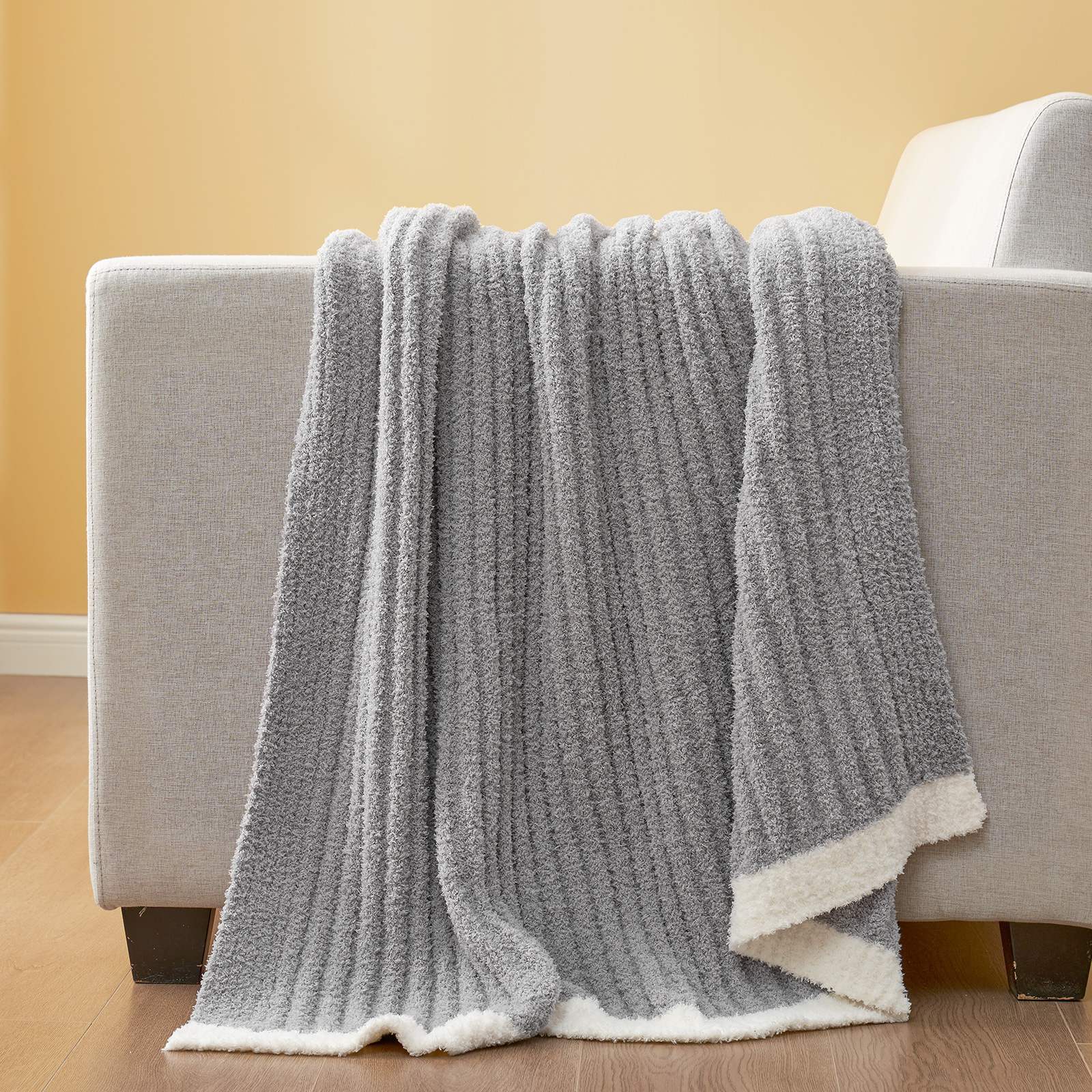 Snuggle Sac UltraSoft Ribbed Feather Yarn Knit Throw Blanket draped on the sofa #Color_Grey