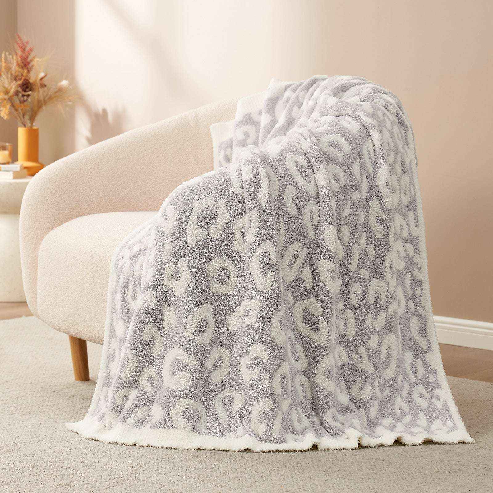 Reversible Leopard Feather Yarn Knit Throw Blanket on a beige couch in a bright room #Color_Leopard Grey