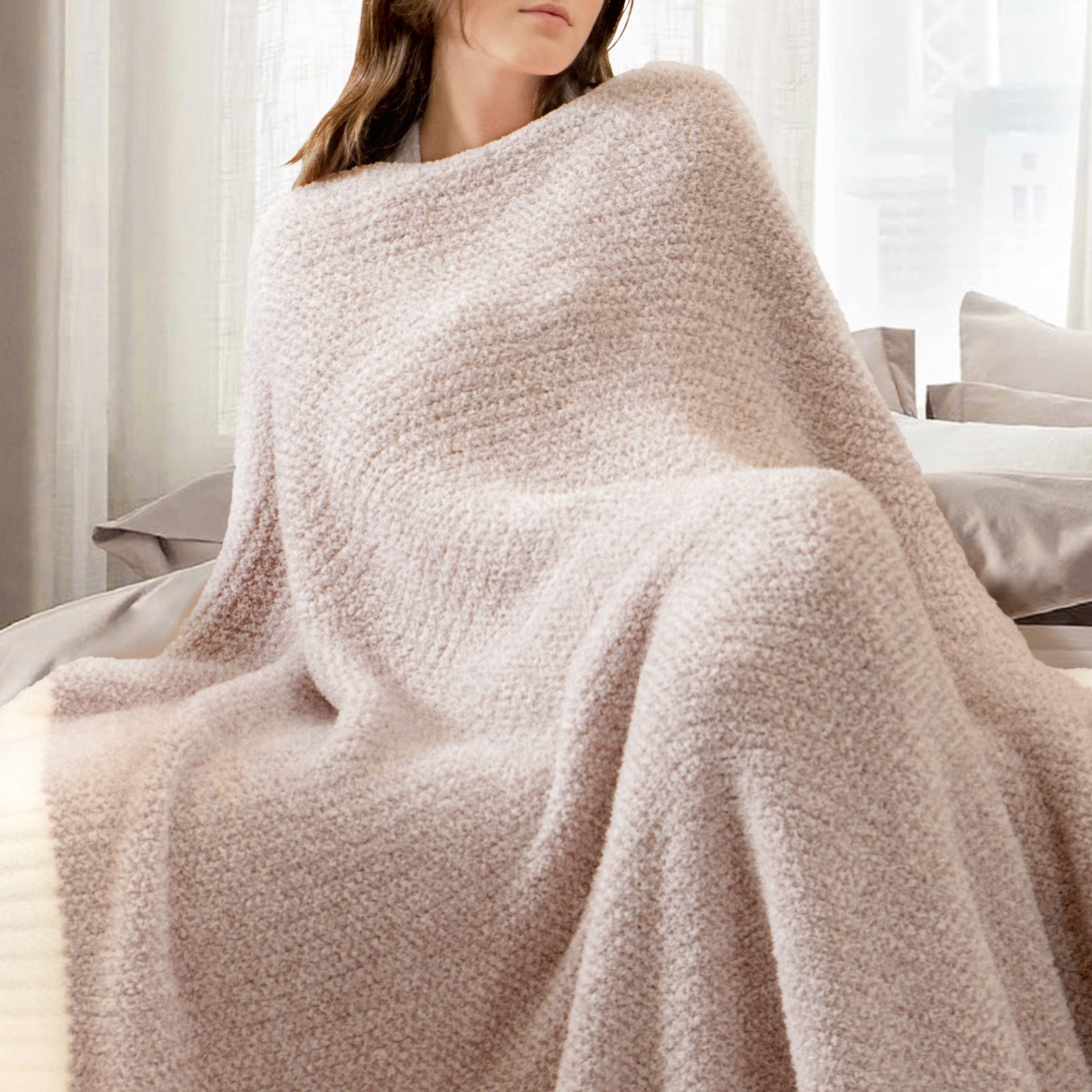 A woman wrapped in Snuggle Sac Heather Feather Yarn Taupe Knit Throw Blanket #Color_Taupe