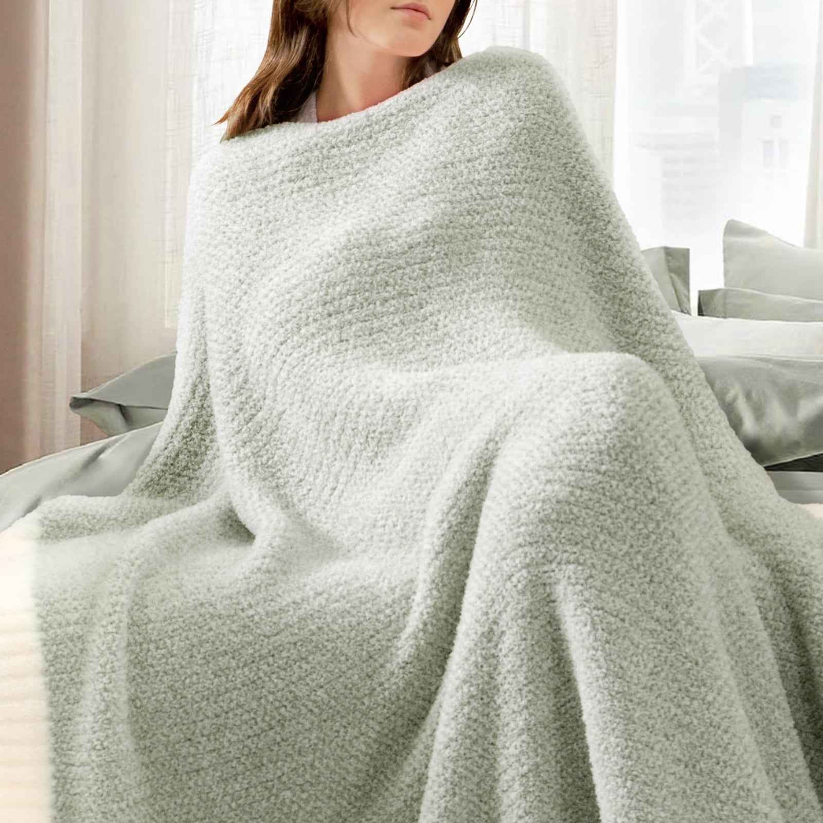 A woman wrapped in Snuggle Sac Heather Feather Yarn sage green Knit Throw Blanket #Color_Sage Green