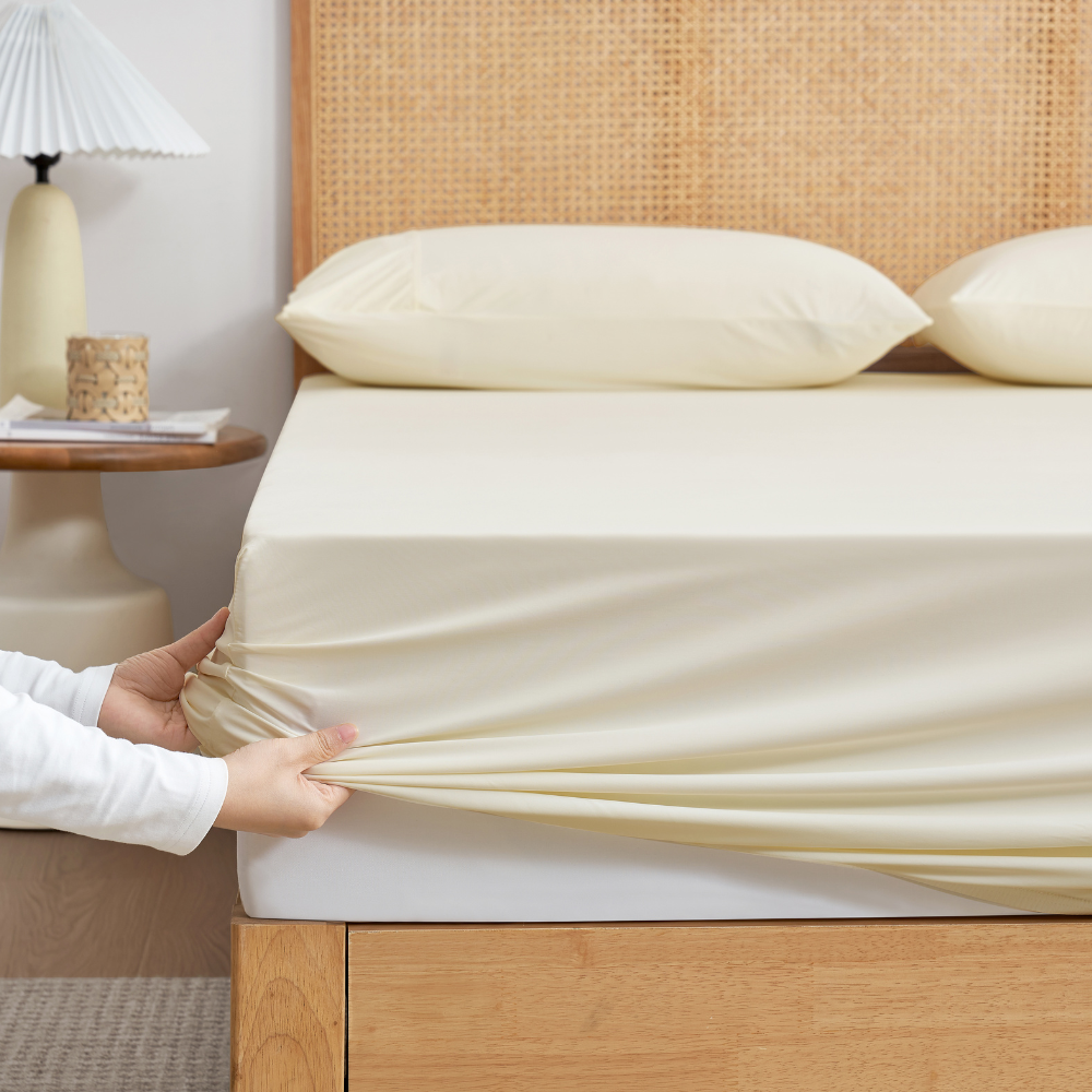 Fitted Snuggle Sac sheet close-up on a bed with wooden headboard, highlighting the snug fit around mattress corners#color_White